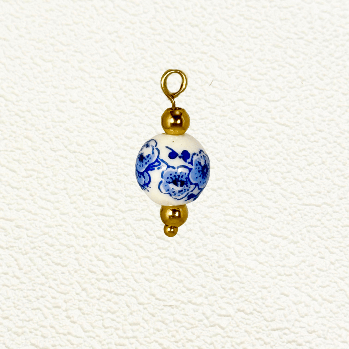 White ceramic charm with blue blossom floral design and gold beads