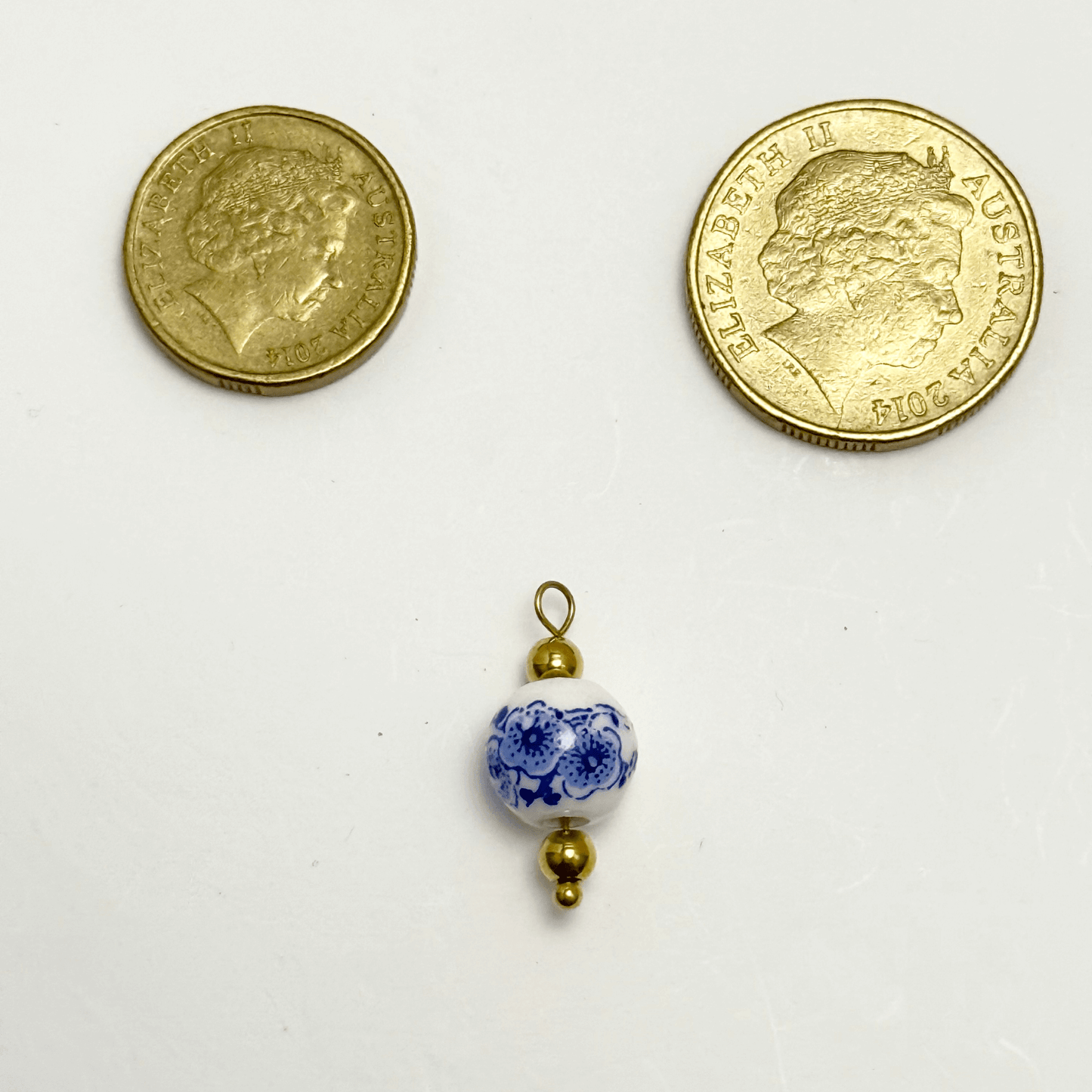 White ceramic charm with blue blossom floral design and gold beads