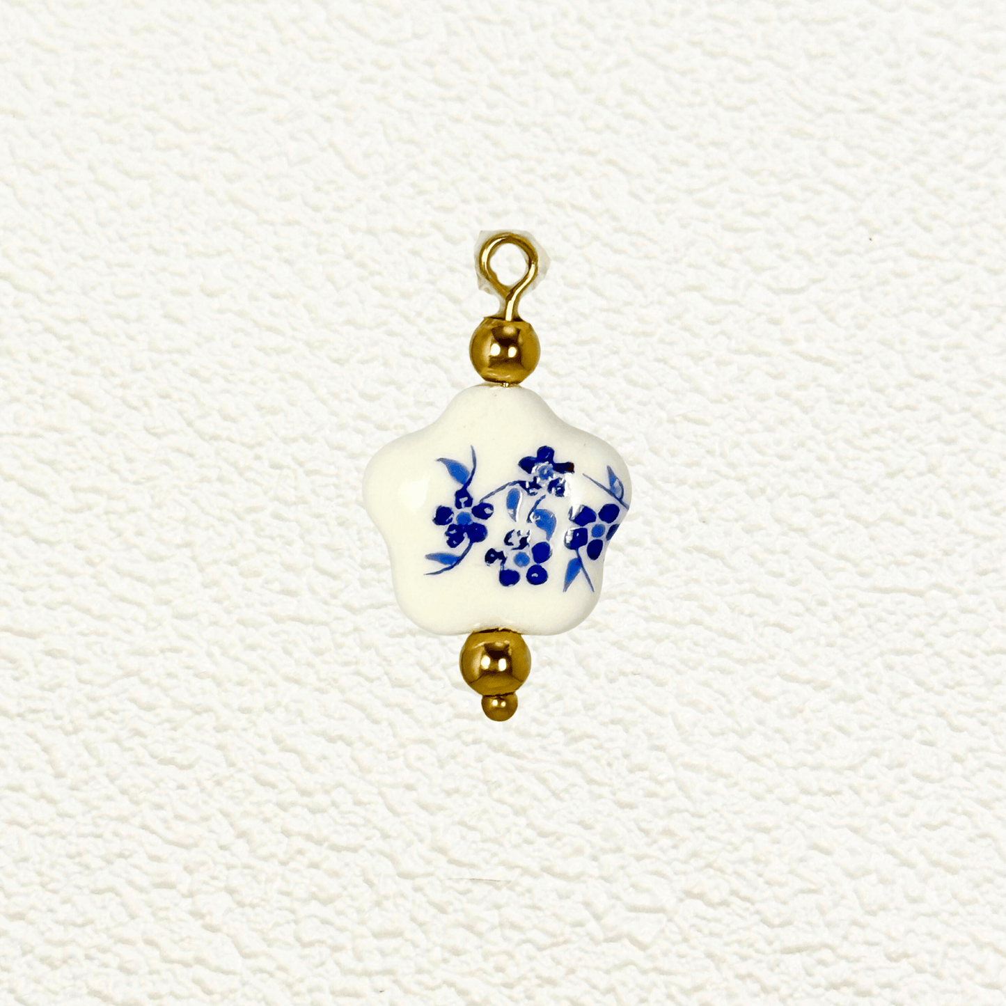 Star-shaped white ceramic charm with blue floral design and gold bead accents