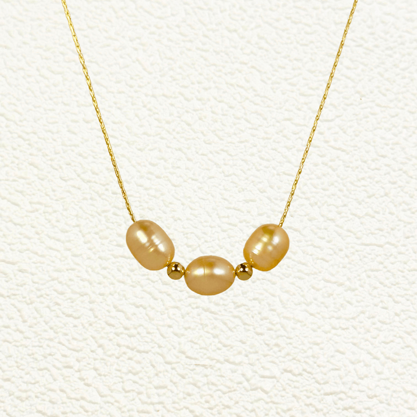 Blush pink freshwater pearl necklace with three pearls on a fine chain, available in gold filled and sterling silver options.