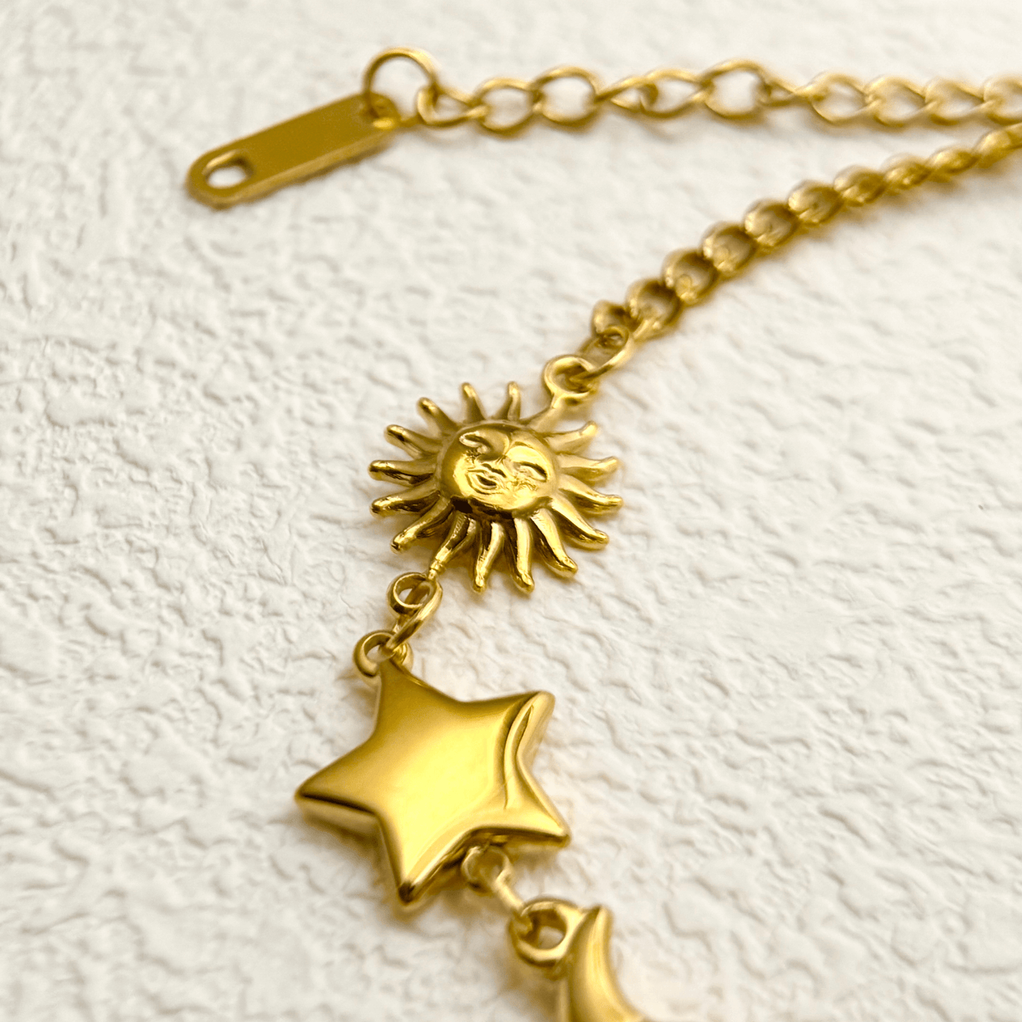 Waterproof gold celestial charm bracelet featuring sun, star, and crescent moon charms, made from PVD gold-plated stainless steel with an adjustable chain