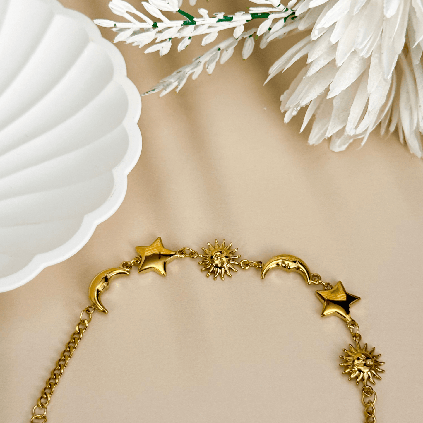 Waterproof gold celestial charm bracelet featuring sun, star, and crescent moon charms, made from PVD gold-plated stainless steel with an adjustable chain