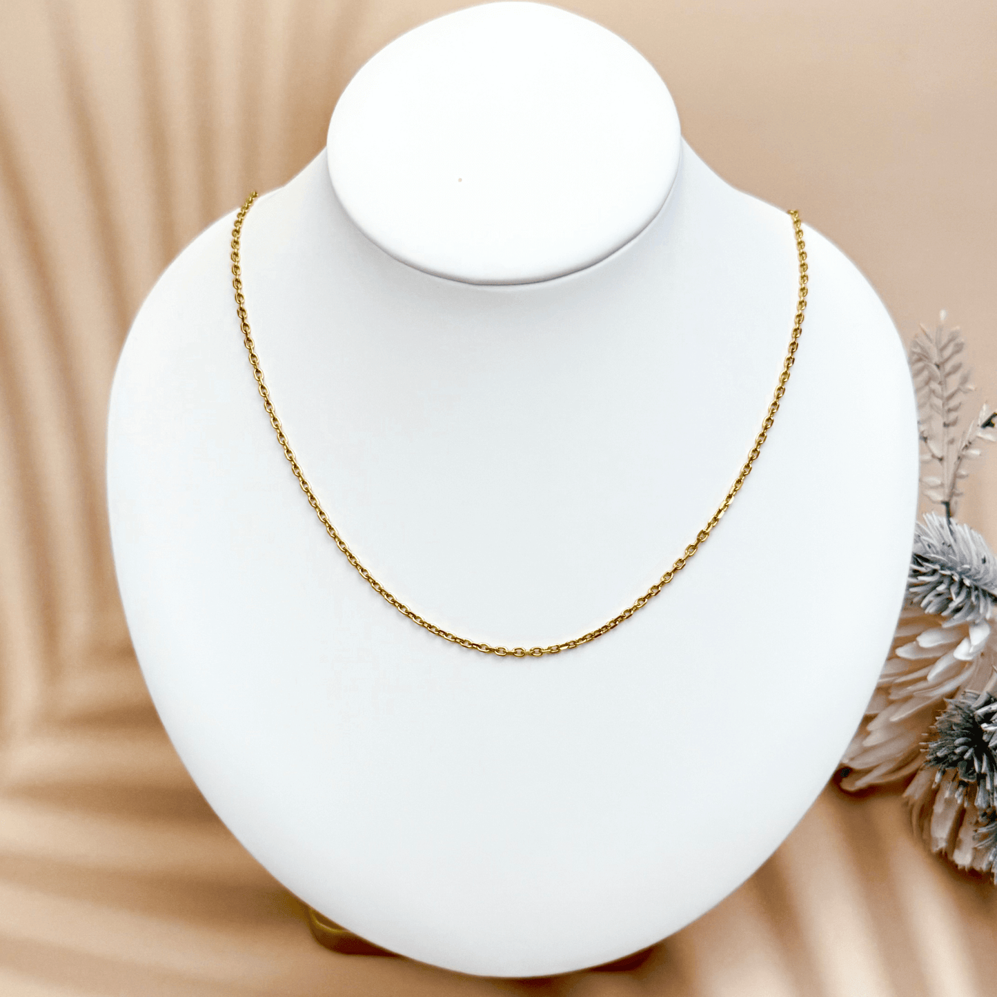 Gold cable chain made of fine interlocking links in a classic minimalist style, available as necklace, bracelet, or anklet