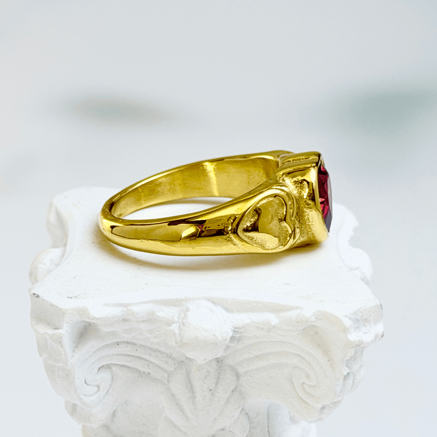 gold signet ring with a red heart-shaped stone in the centre