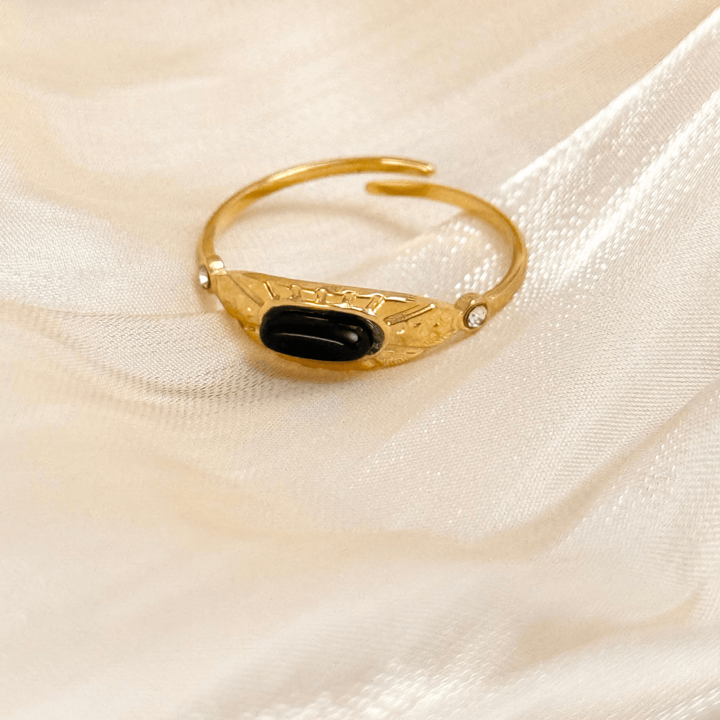 Orion gold ring with oval black agate stone and sunburst engraving, adjustable open band design.