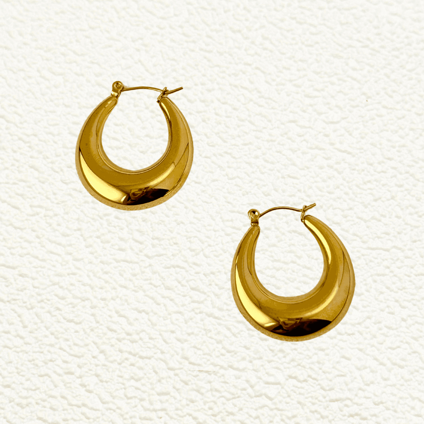 Gold crescent hoop earrings in sculptural design, made from PVD-plated stainless steel, bold modern statement jewelry for women