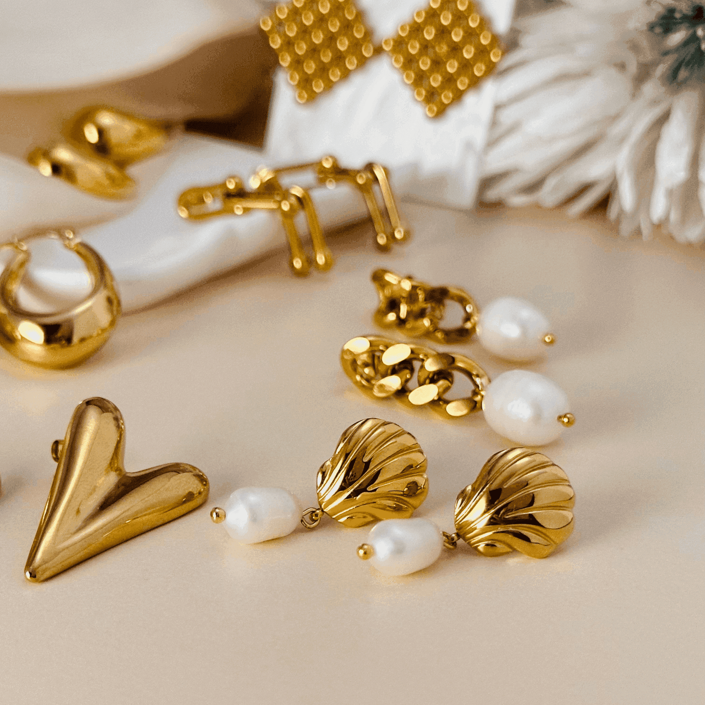A collection of gold earrings featuring bold, modern, and pearl-accented designs, including hoops, hearts, and sculptural styles. Perfect for statement and elegant looks.