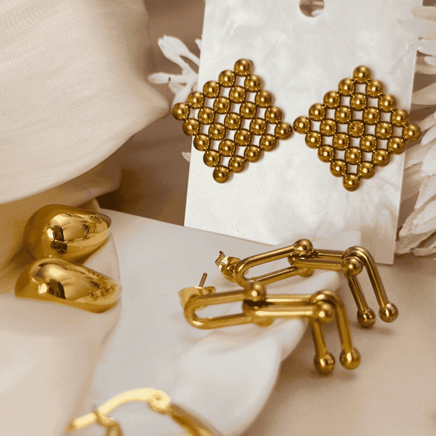 A collection of gold earrings featuring bold, modern, and pearl-accented designs, including hoops, hearts, and sculptural styles. Perfect for statement and elegant looks.