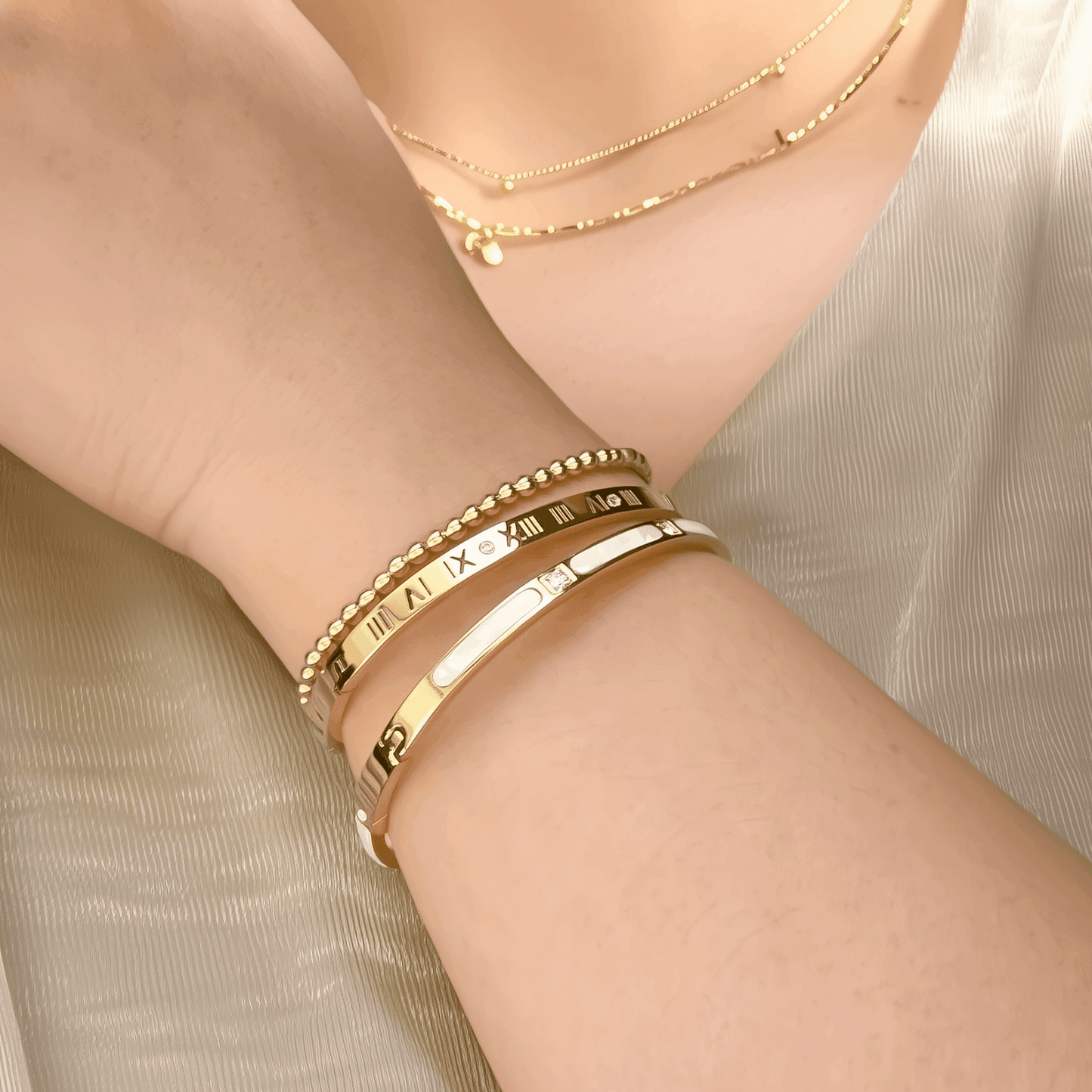 A collection of gold-plated bangles from MXW Jewellery, featuring zircon accents, Roman numerals, and smooth polished finishes, waterproof and tarnish-free.