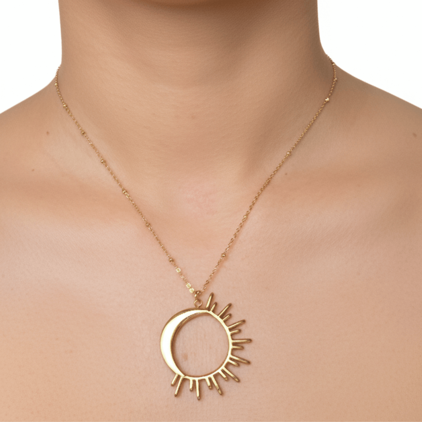 Waterproof gold solar eclipse necklace featuring a crescent moon overlapping a radiant sunburst design on a fine beaded chain, made with PVD gold plated stainless steel.