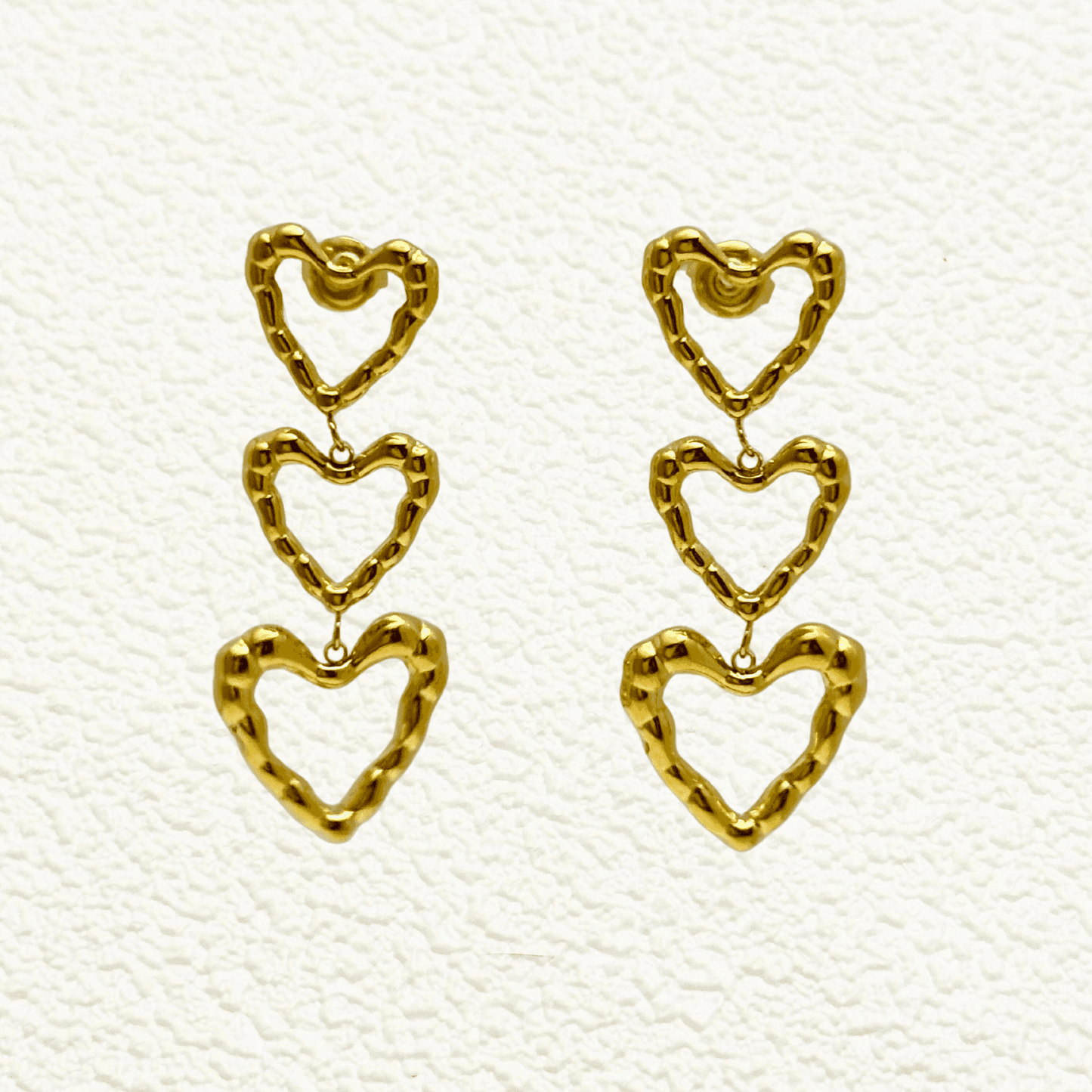 Gold triple heart drop earrings in waterproof stainless steel with a textured design