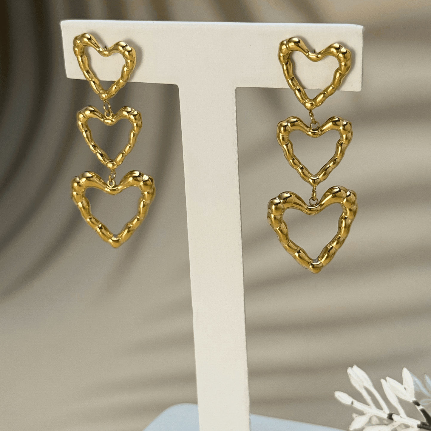 Gold triple heart drop earrings in waterproof stainless steel with a textured design