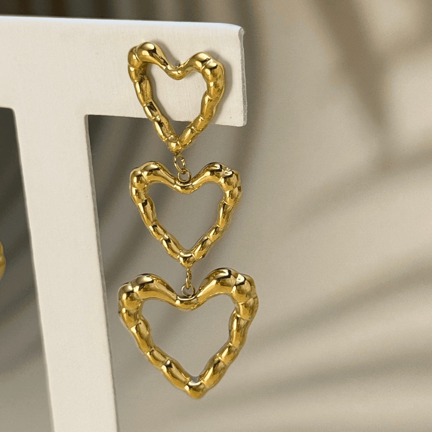 Gold triple heart drop earrings in waterproof stainless steel with a textured design