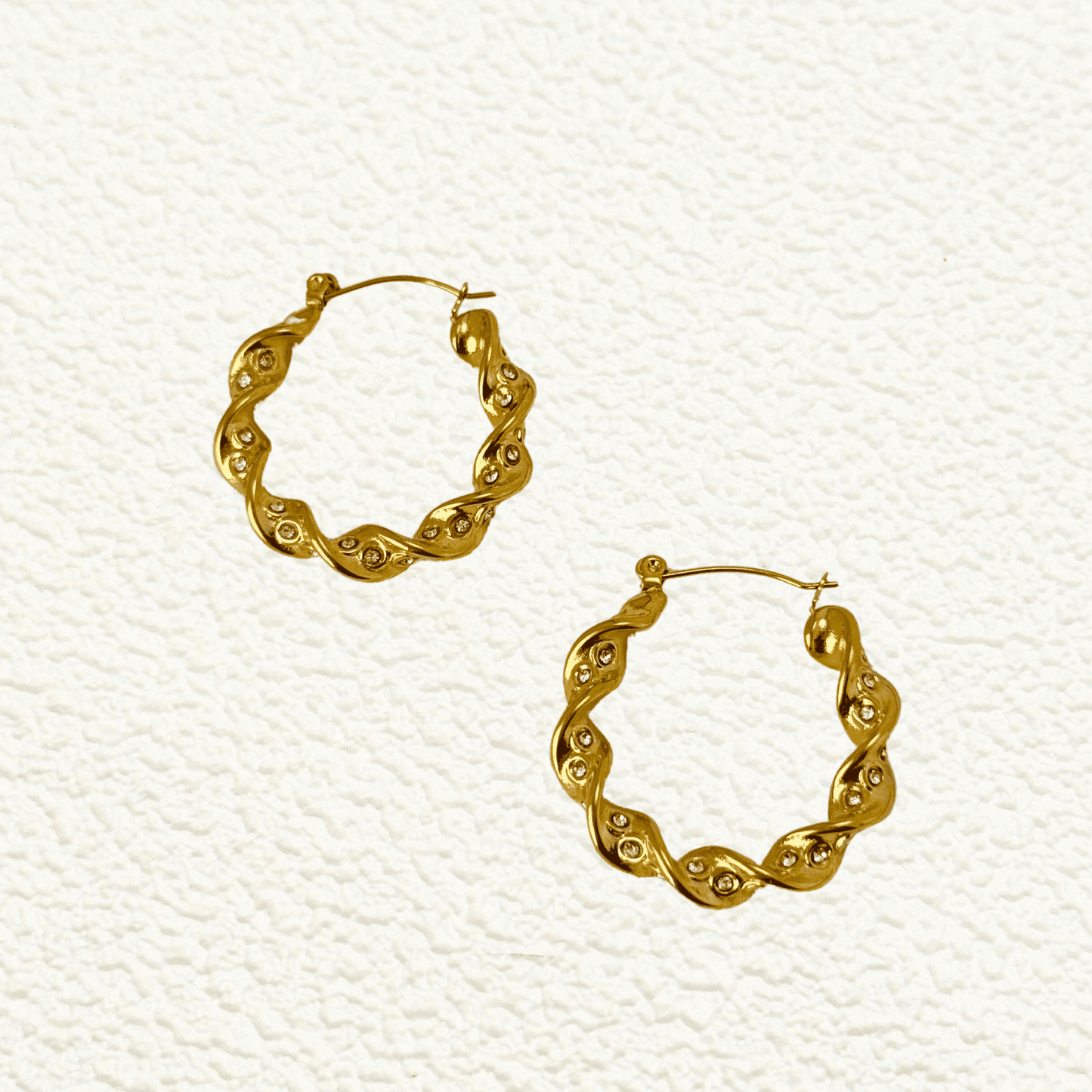 Gold twisted zircon hoop earrings made of waterproof stainless steel with a wave-like design and sparkling zircon stones.