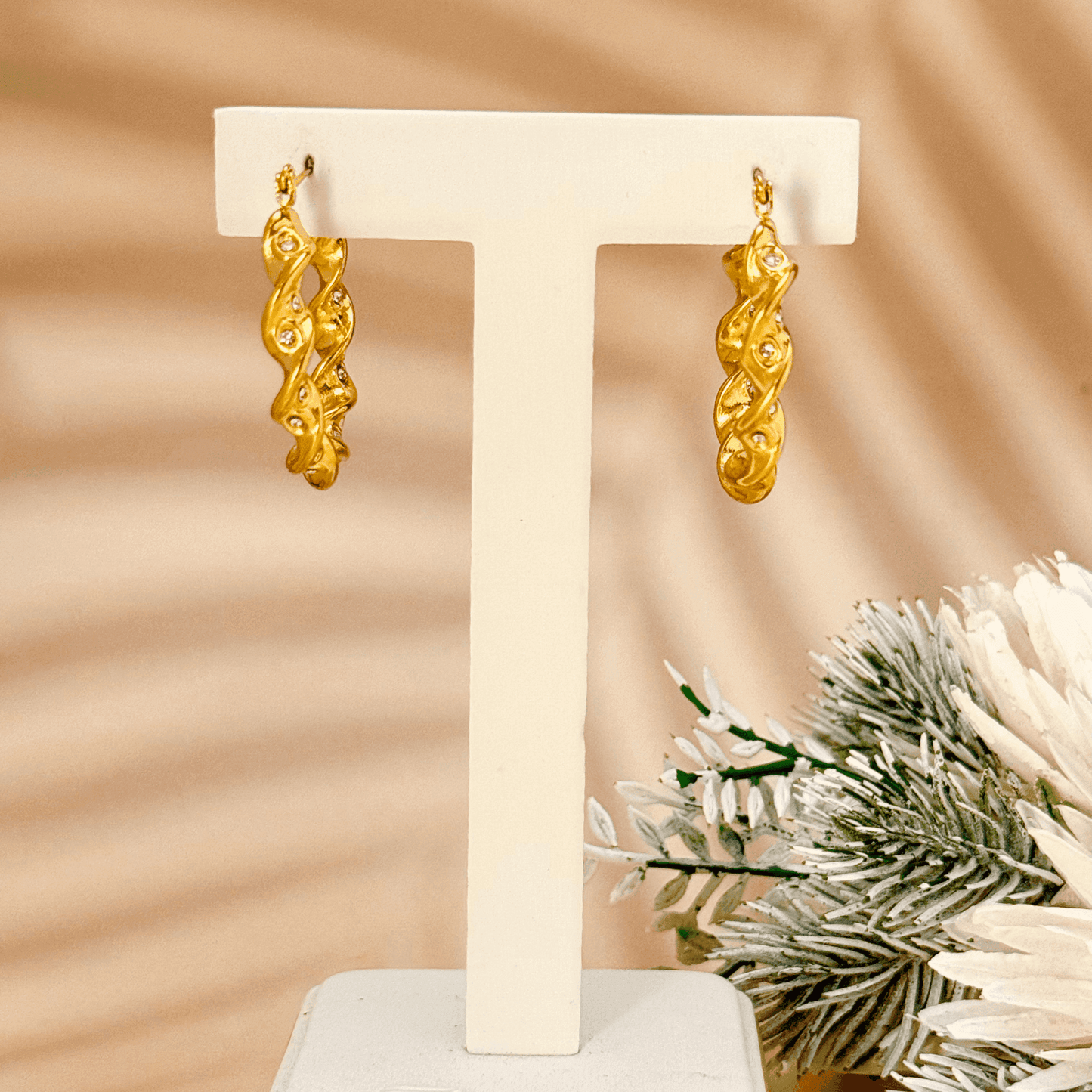 Gold twisted zircon hoop earrings made of waterproof stainless steel with a wave-like design and sparkling zircon stones.