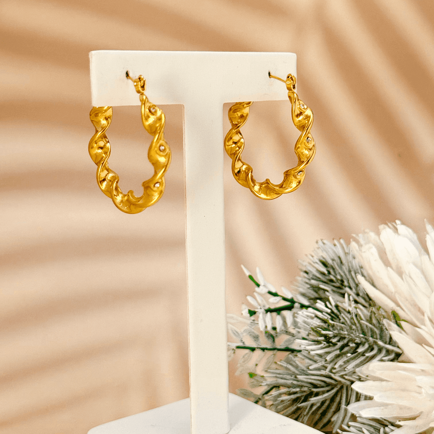 Gold twisted zircon hoop earrings made of waterproof stainless steel with a wave-like design and sparkling zircon stones.