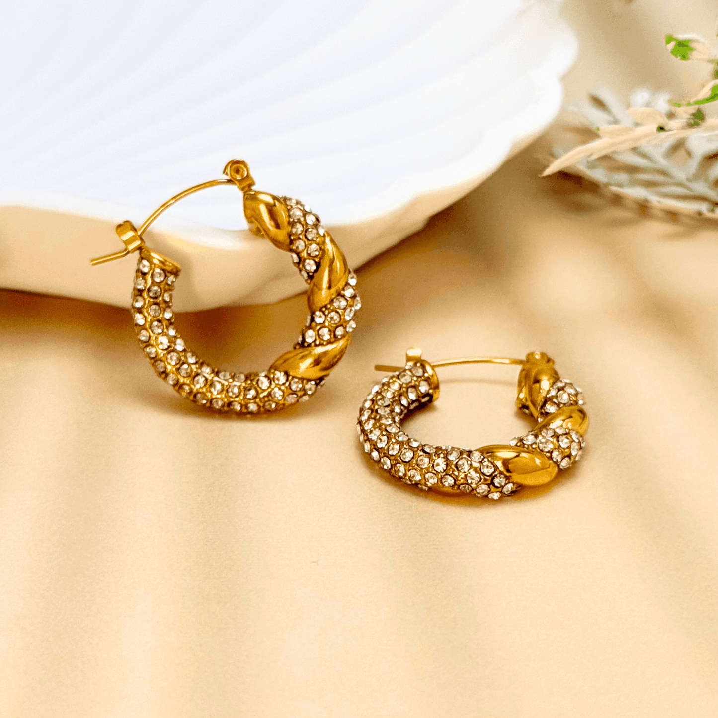 Gold twisted hoop earrings with zircon stones, crafted from PVD gold-plated stainless steel. Elegant, sparkling, and waterproof design for everyday wear.