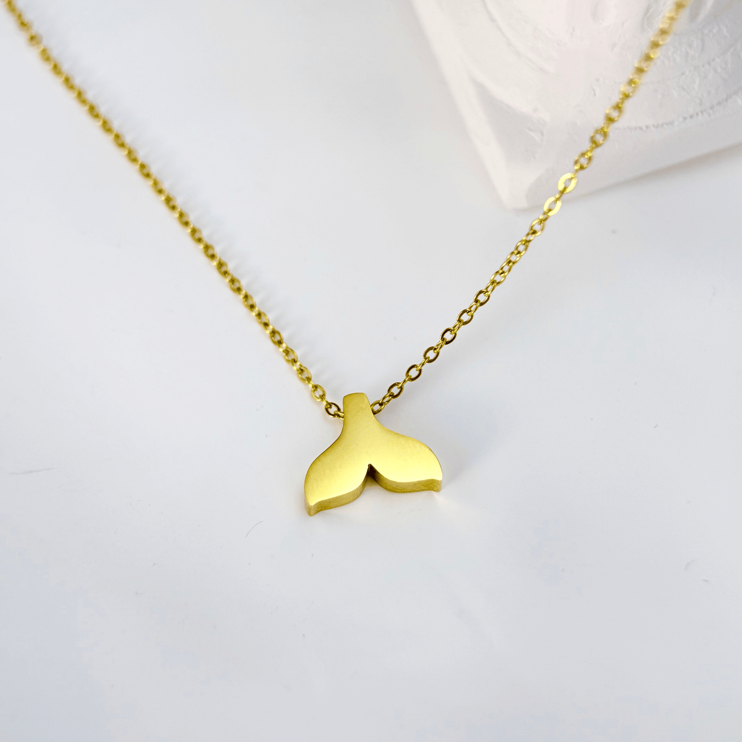 Gold whale tail pendant necklace symbolising ocean strength and freedom.
