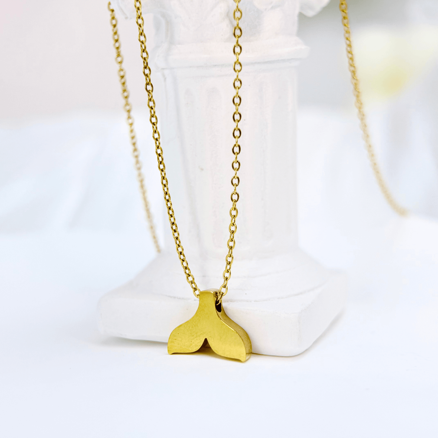 Gold whale tail pendant necklace symbolising ocean strength and freedom.