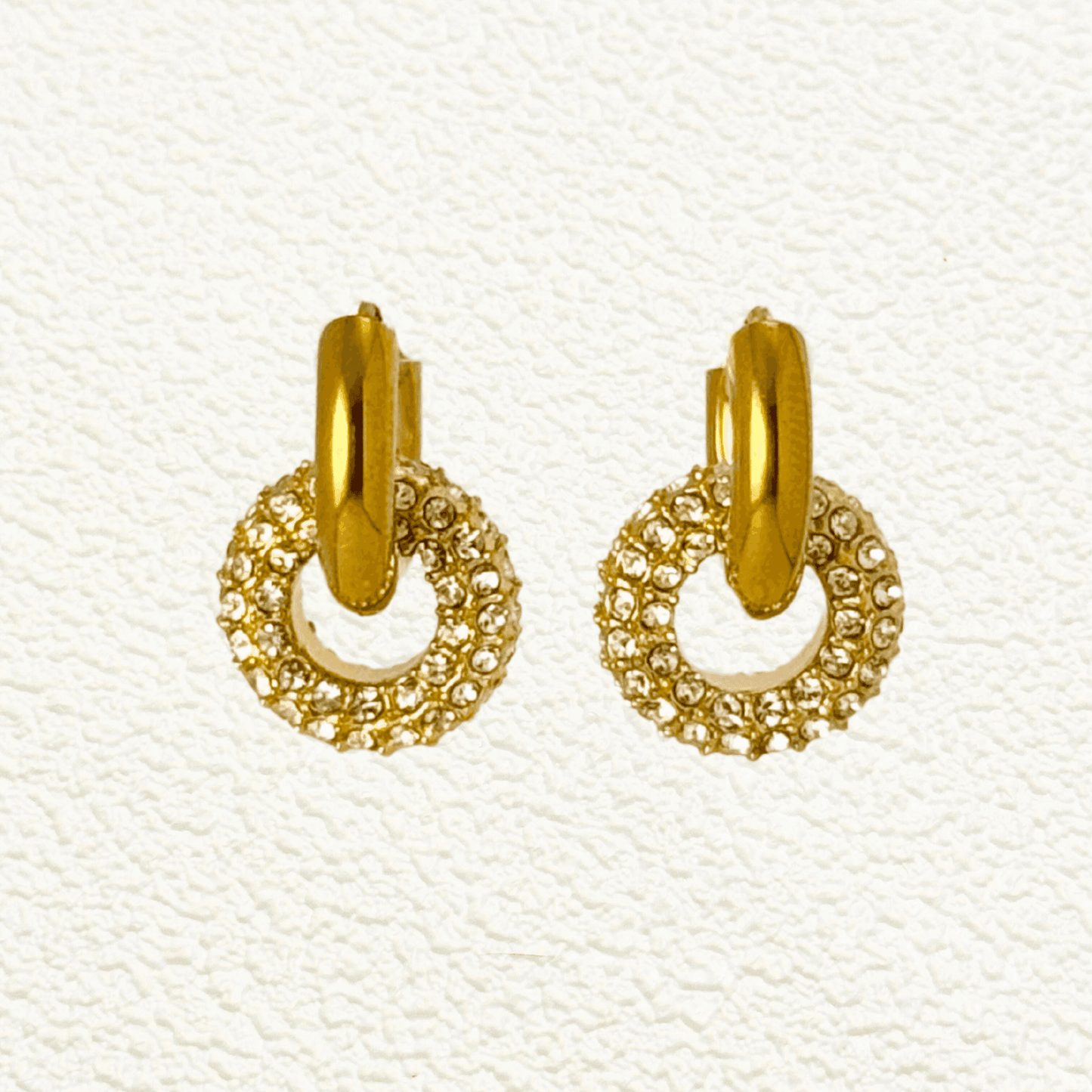 Gold hoop earrings with sparkling zircon-studded round drop pendant, elegant geometric design on display stand