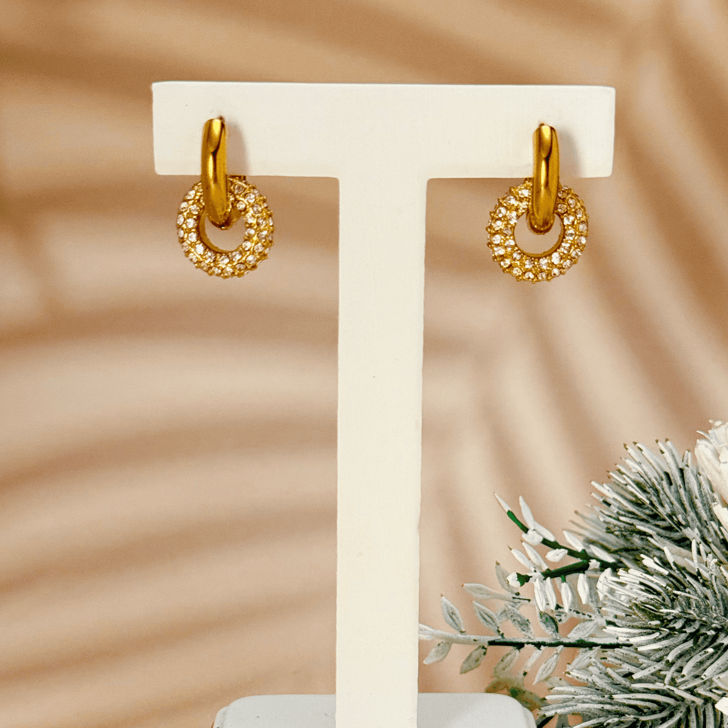 Gold hoop earrings with sparkling zircon-studded round drop pendant, elegant geometric design on display stand