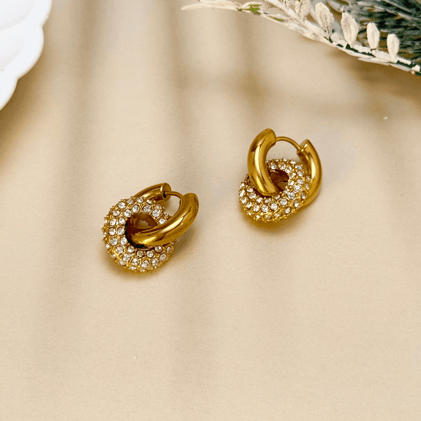 Gold hoop earrings with sparkling zircon-studded round drop pendant, elegant geometric design on display stand