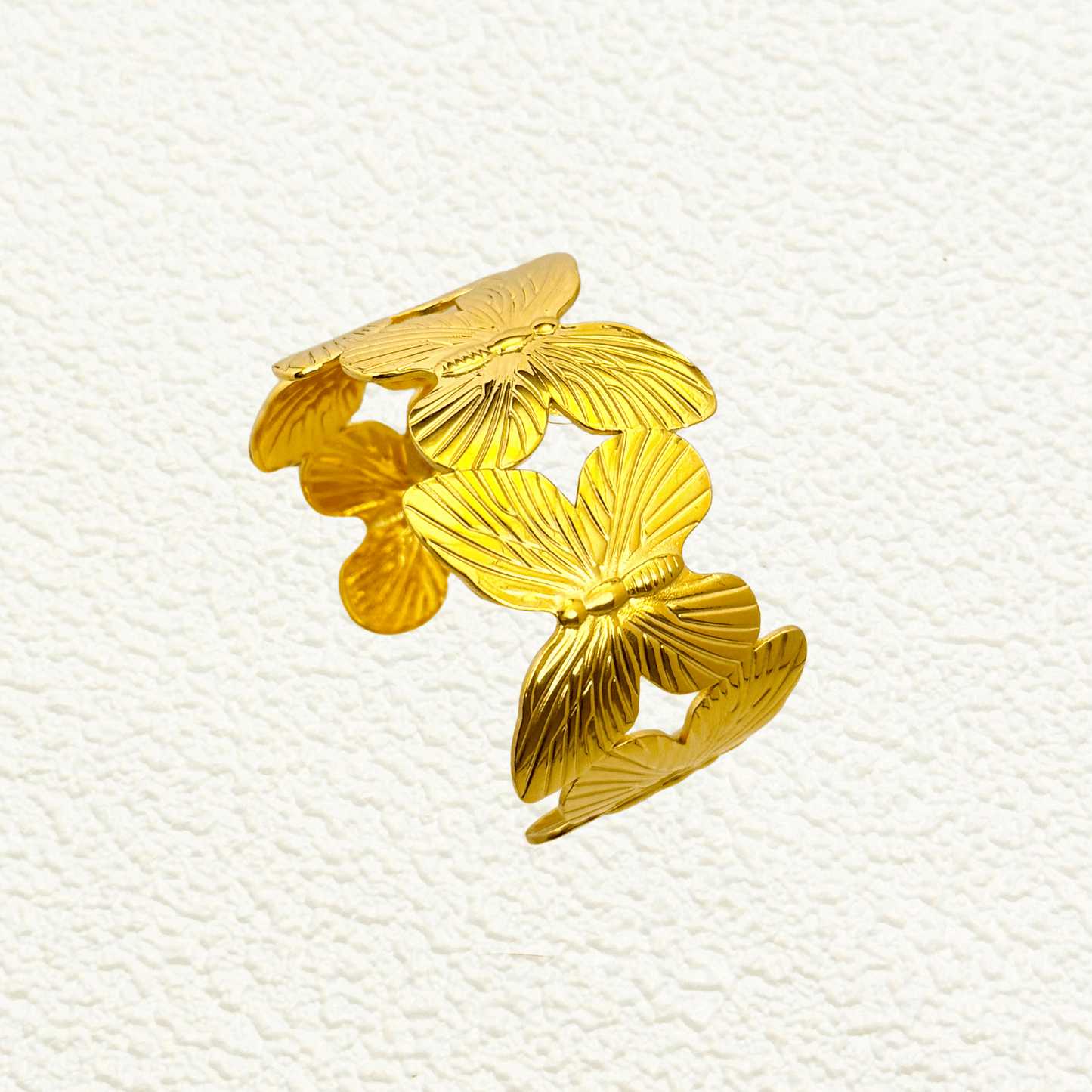Waterproof gold butterfly bangle bracelet featuring layered sculpted butterflies in a detailed garden-inspired open cuff design, made with PVD gold plated stainless steel.