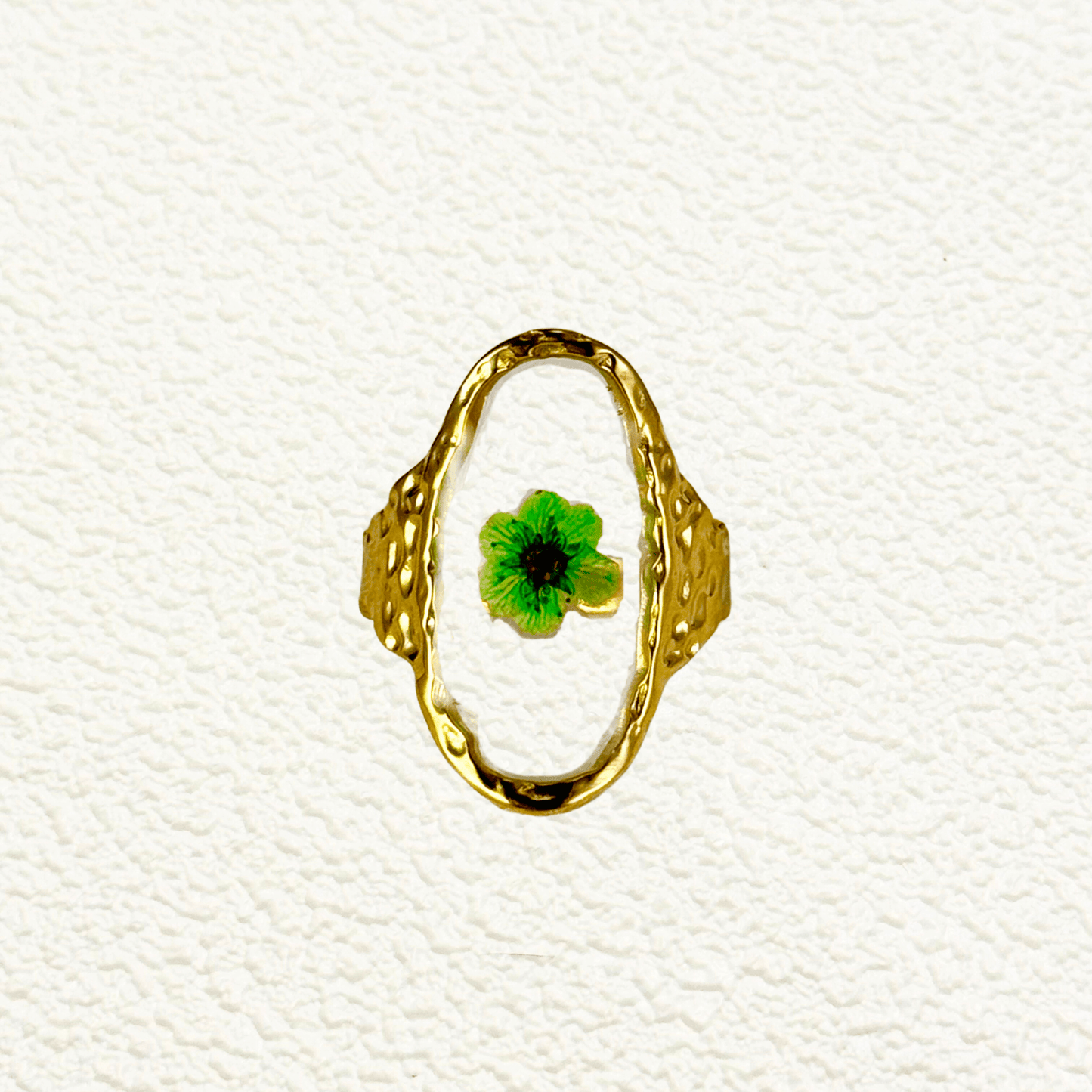 Gold ring with real dried green flower encased in oval frame, waterproof and botanical-inspired design.