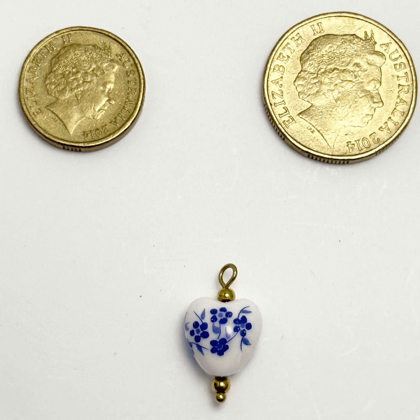 Heart-shaped ceramic charm with small blue flowers and gold bead details