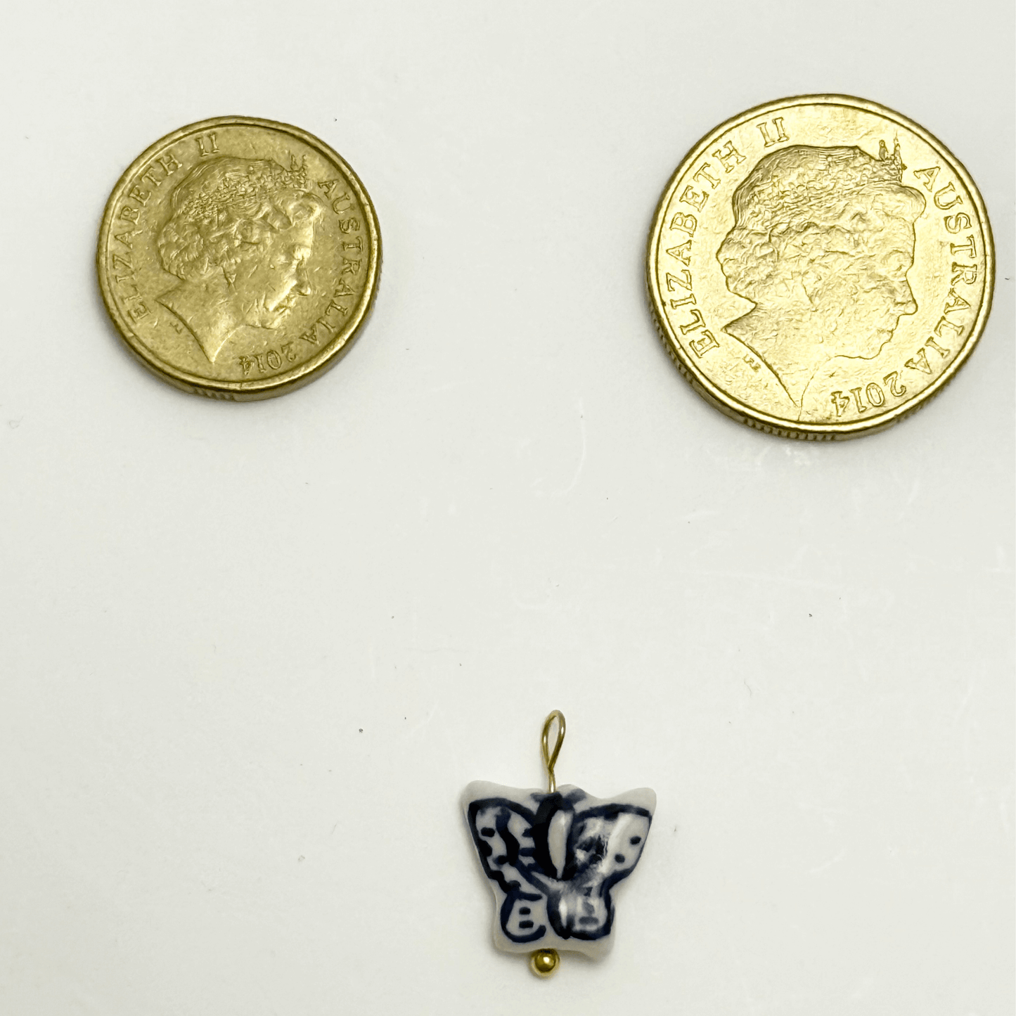 Blue and white ceramic butterfly charm with abstract wing patterns and gold loop