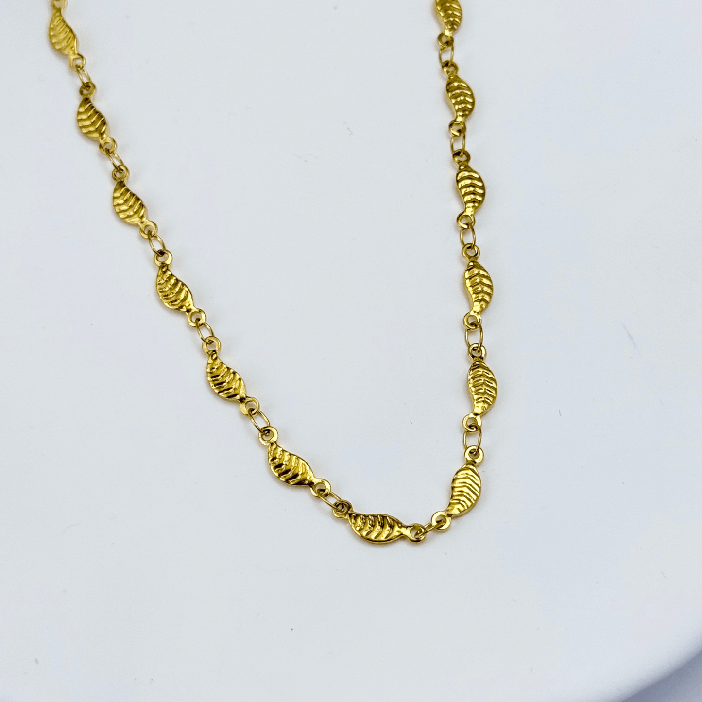 Elegant waterproof gold chain featuring textured leaf links with a minimalist, nature-inspired design
