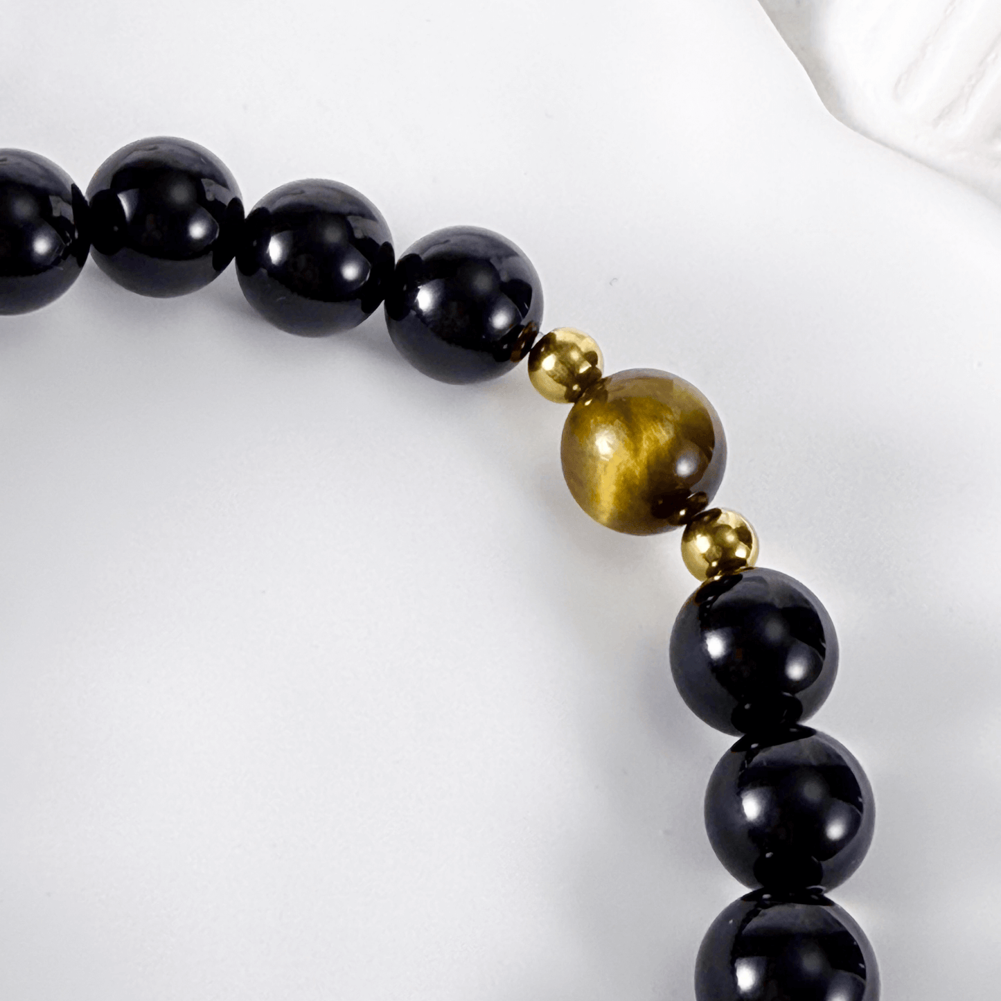Men’s bracelet with polished black agate beads, single tiger’s eye gemstone, and gold accents on stretch cord.