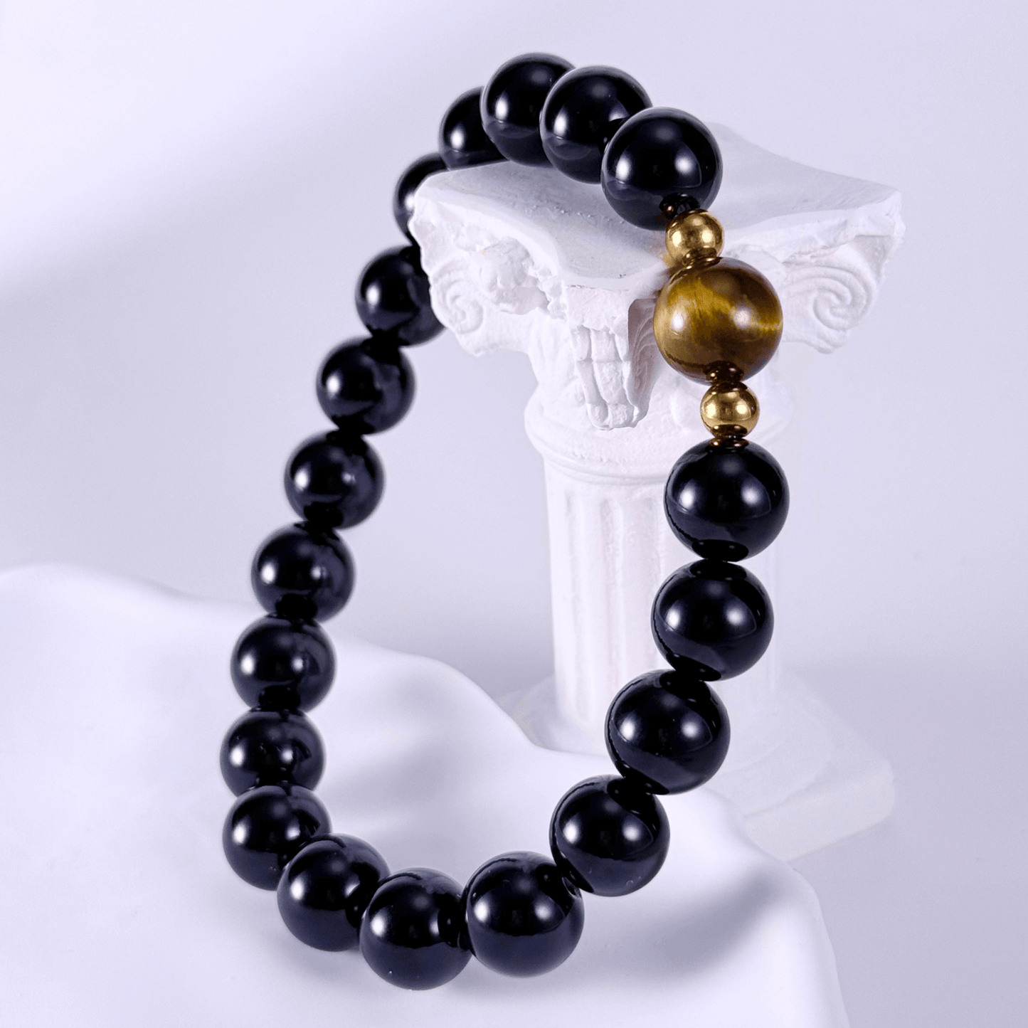 Men’s bracelet with polished black agate beads, single tiger’s eye gemstone, and gold accents on stretch cord.