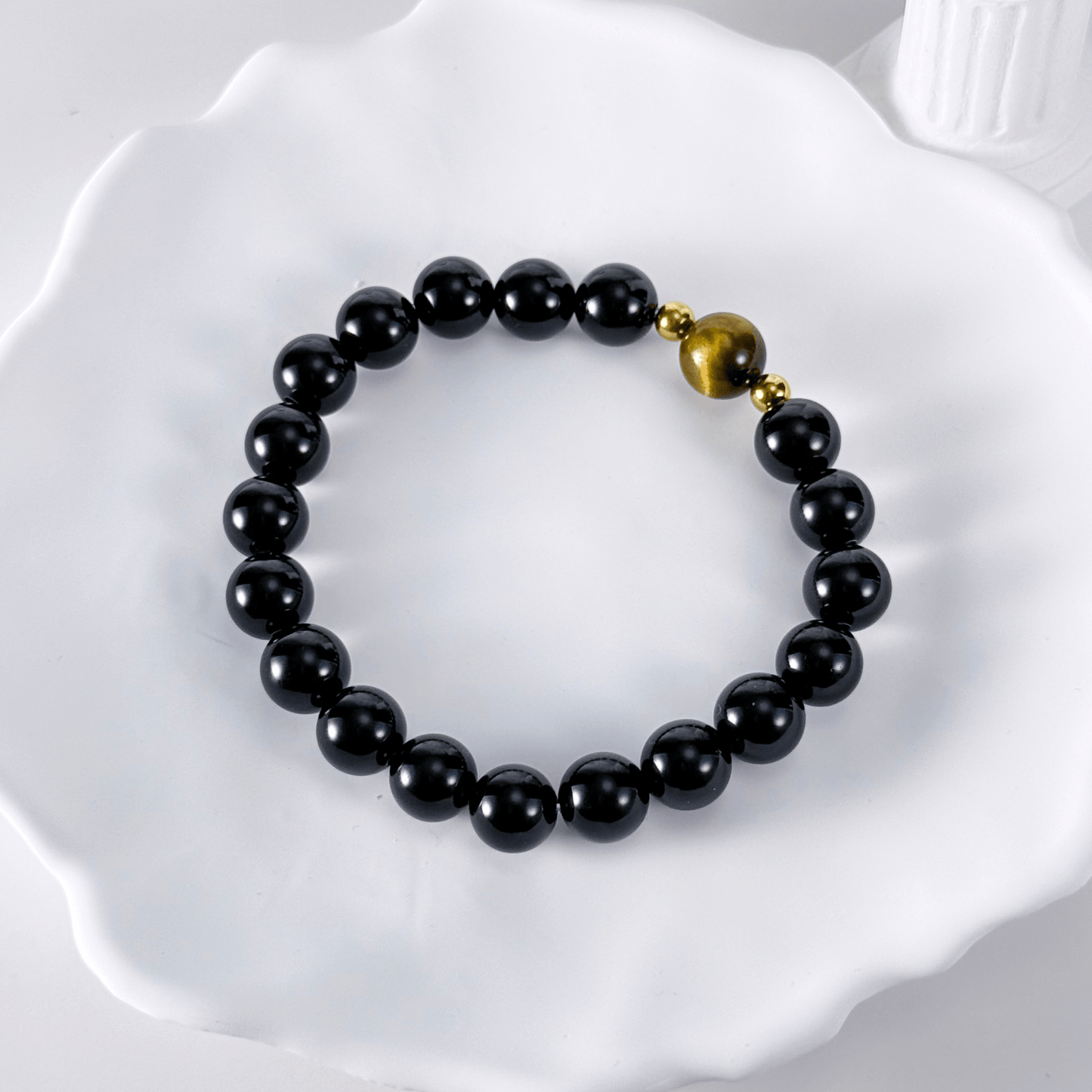 Men’s bracelet with polished black agate beads, single tiger’s eye gemstone, and gold accents on stretch cord.