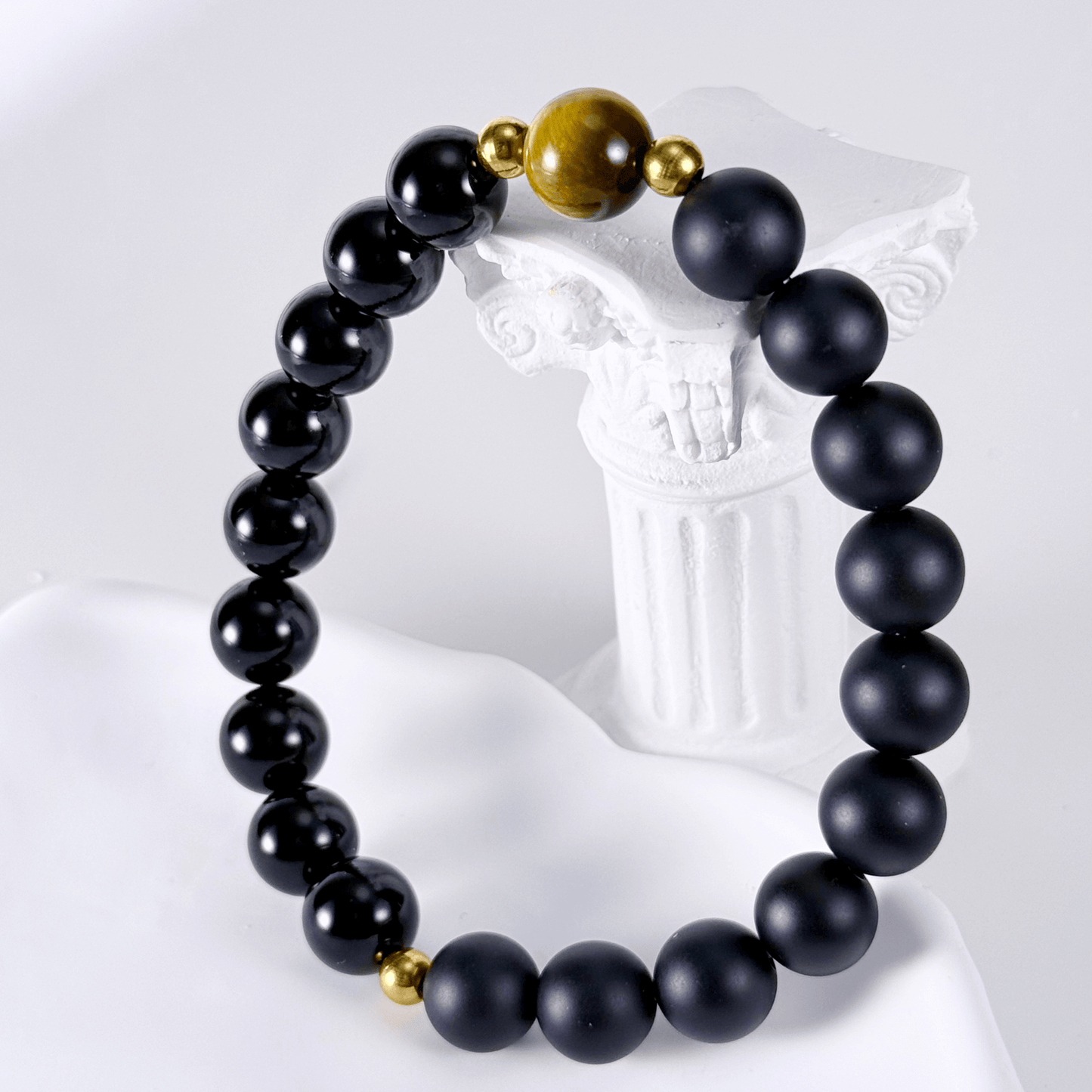 Men’s bracelet with polished black agate beads, single tiger’s eye gemstone, and gold accents on stretch cord.