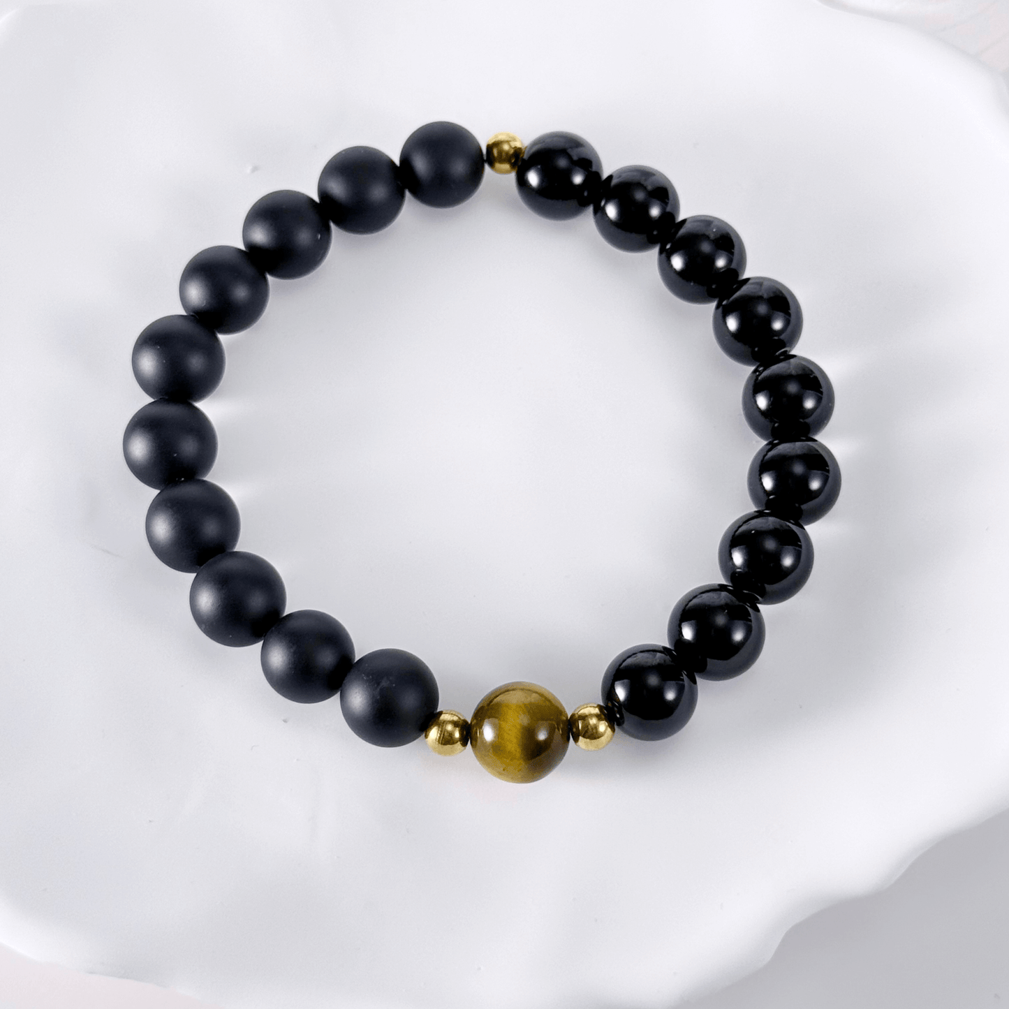 Men’s bracelet with polished black agate beads, single tiger’s eye gemstone, and gold accents on stretch cord.