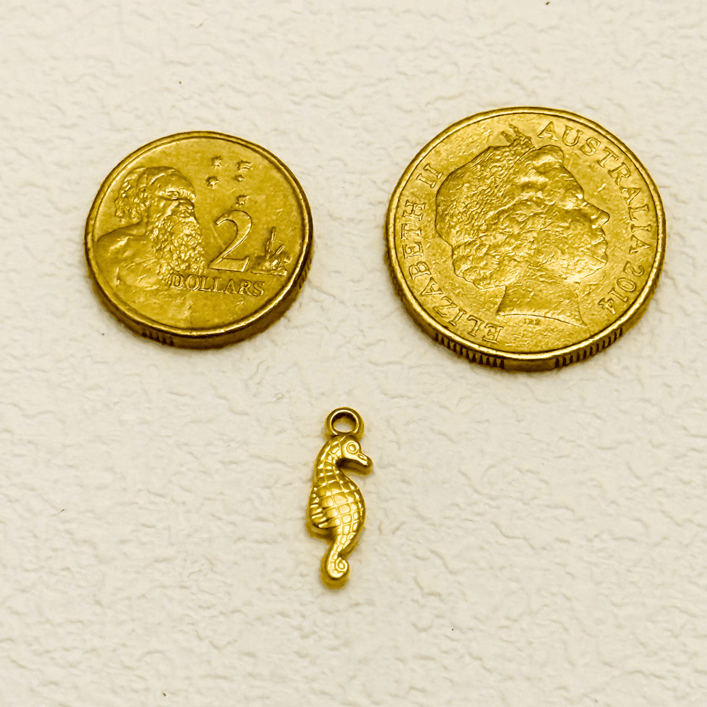 Gold seahorse charm with a textured diamond pattern and curved tail