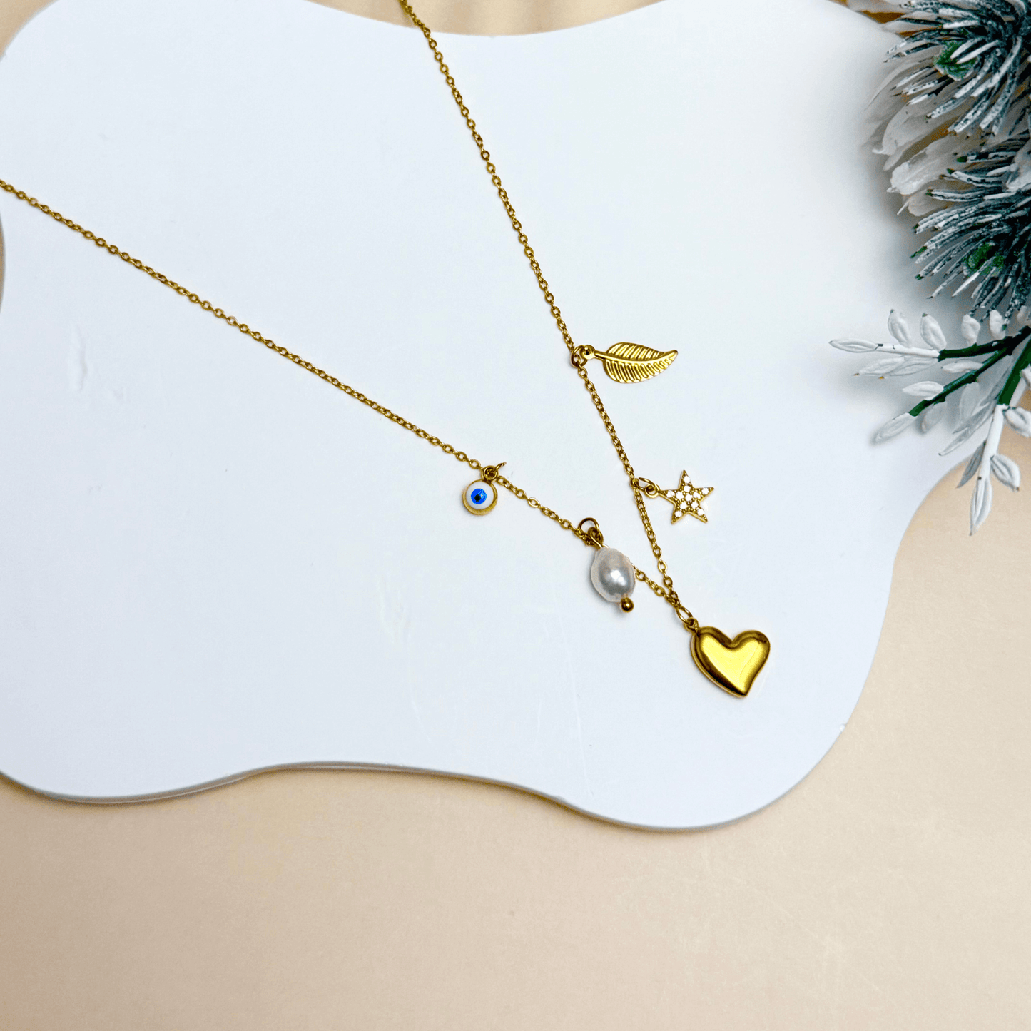 Mini gold charm necklace with evil eye, heart, pearl, star, and leaf on waterproof chain