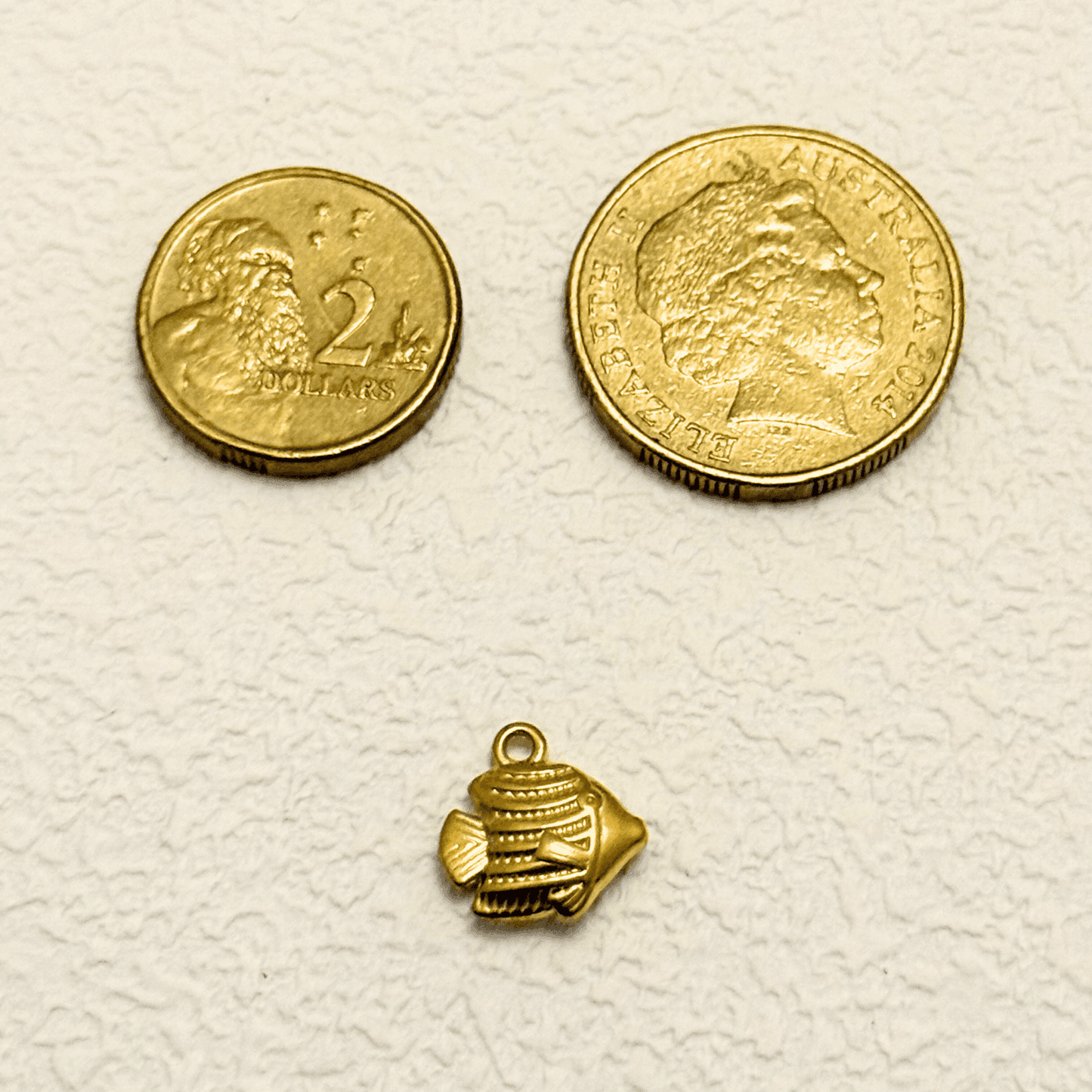 Small gold tropical fish charm with textured detail and solid construction
