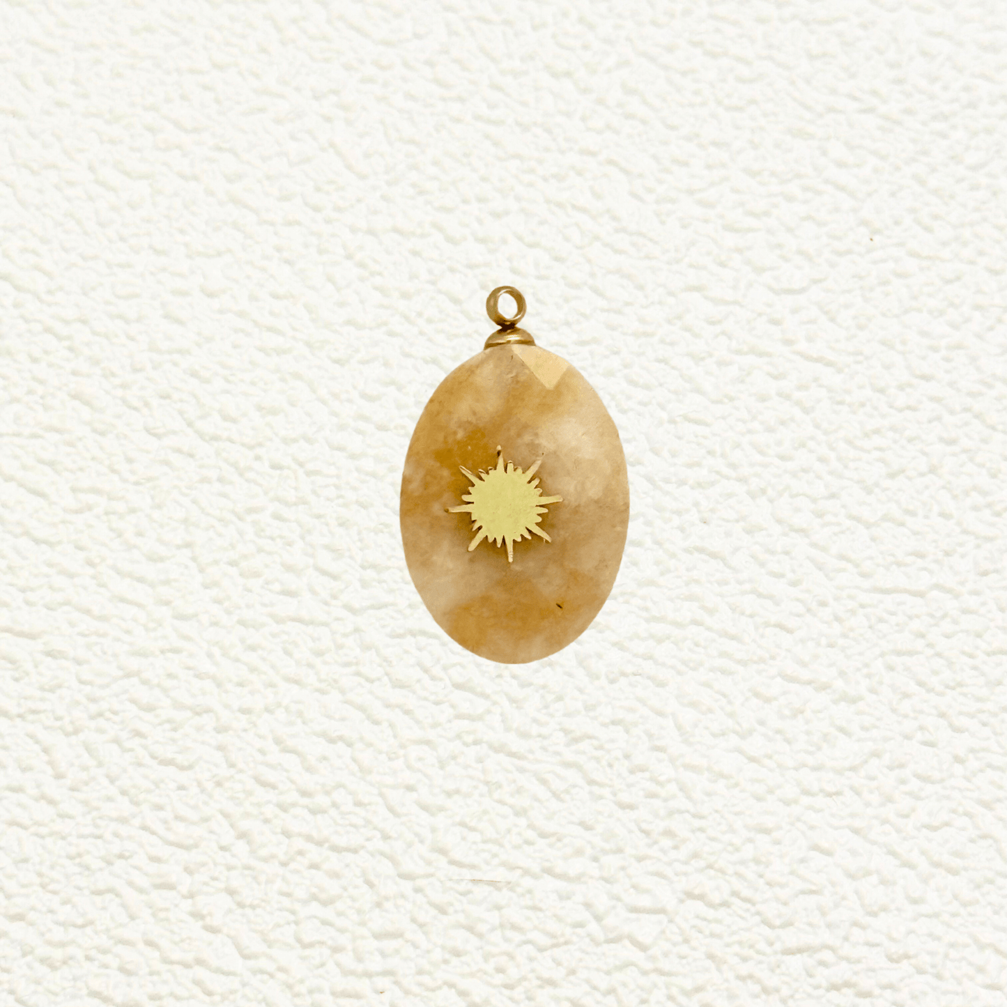 Natural stone oval charm with engraved starburst design, featuring a smooth polished surface and earthy tones, ideal for celestial-themed jewelry.