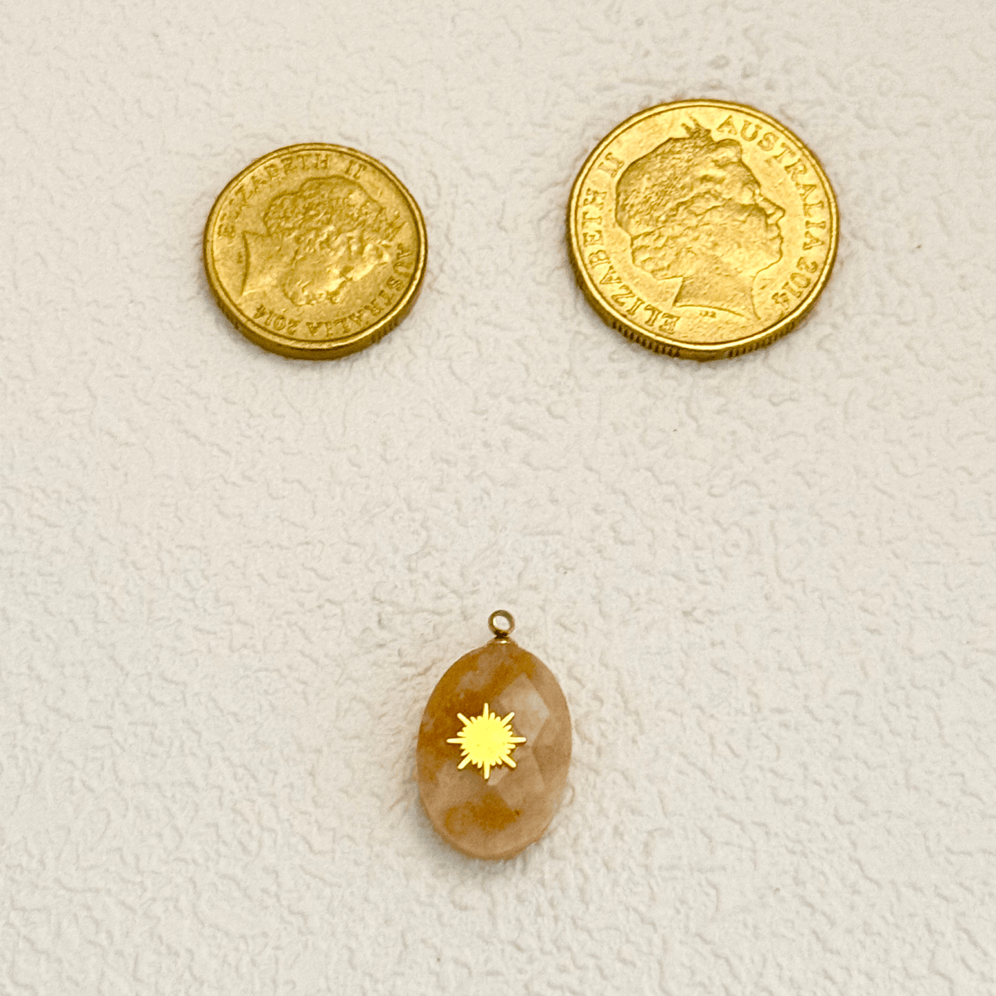 Natural stone oval charm with engraved starburst design, featuring a smooth polished surface and earthy tones, ideal for celestial-themed jewelry.