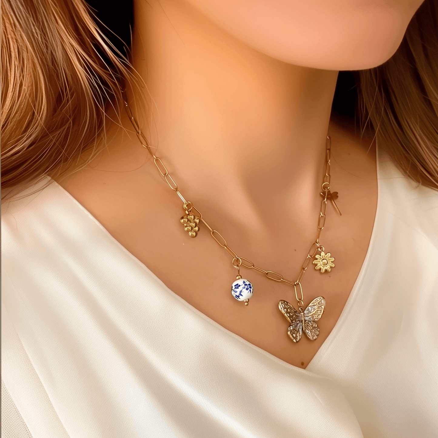 Gold charm necklace with butterfly, daisy, dragonfly, grape, and blue floral bead on waterproof paperclip chain