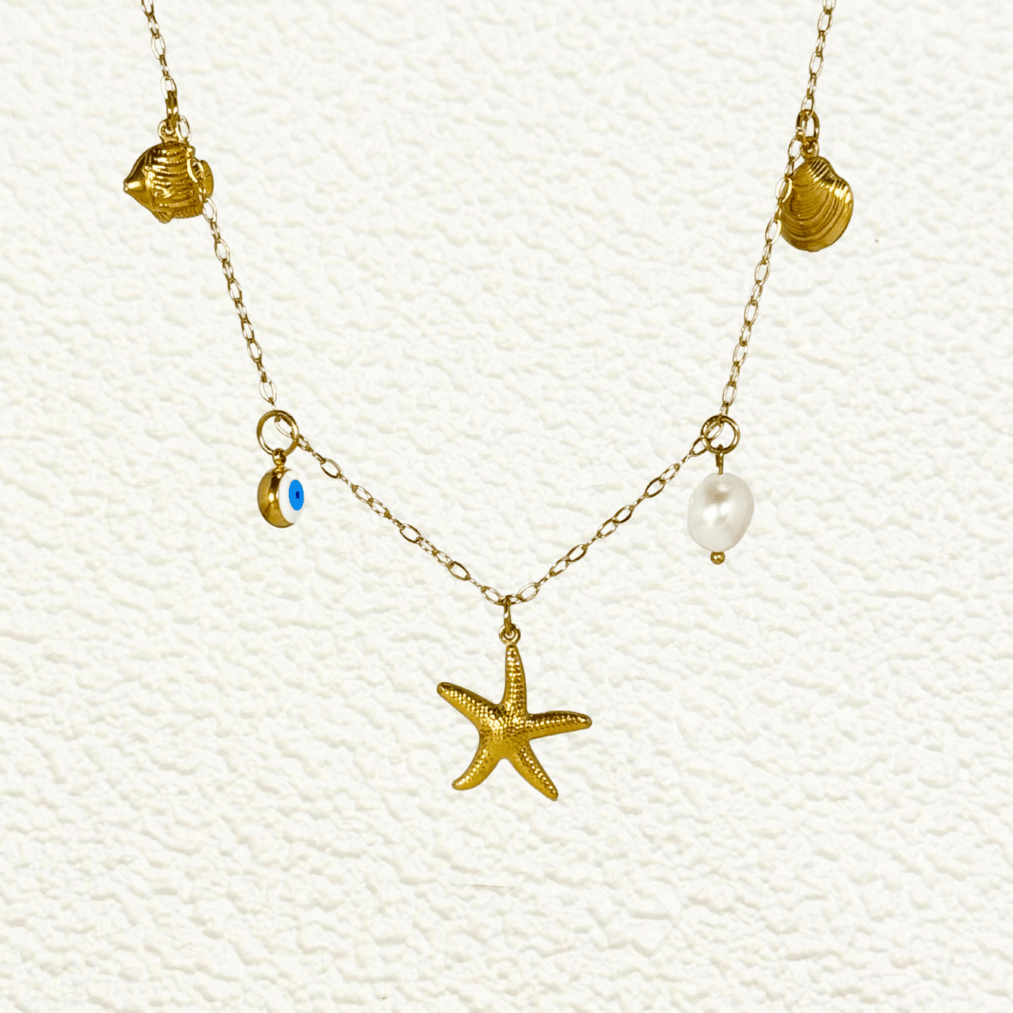 Ocean-inspired gold necklace with starfish, shell, pearl, fish, and evil eye charms