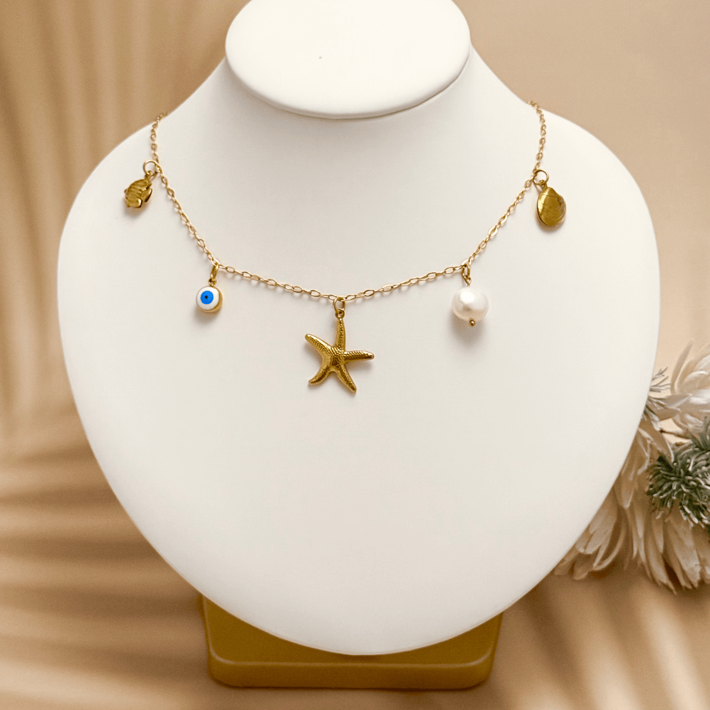 Ocean-inspired gold necklace with starfish, shell, pearl, fish, and evil eye charms