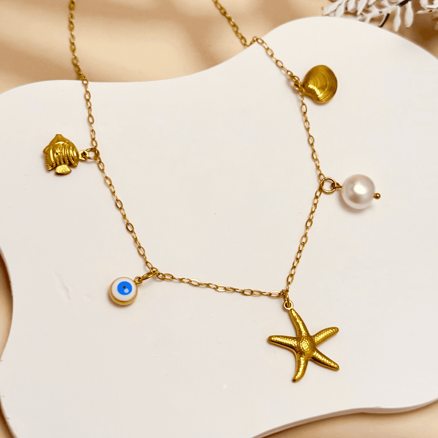 Ocean-inspired gold necklace with starfish, shell, pearl, fish, and evil eye charms