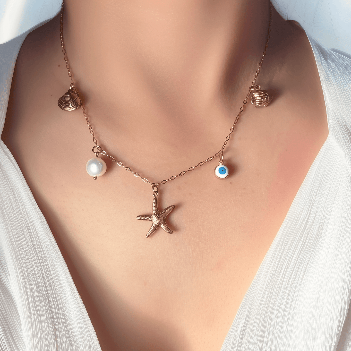 Ocean-inspired gold necklace with starfish, shell, pearl, fish, and evil eye charms