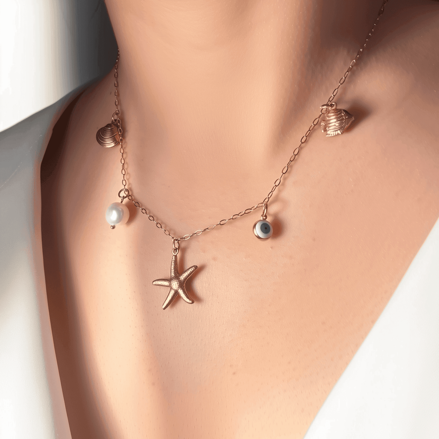 Ocean-inspired gold necklace with starfish, shell, pearl, fish, and evil eye charms