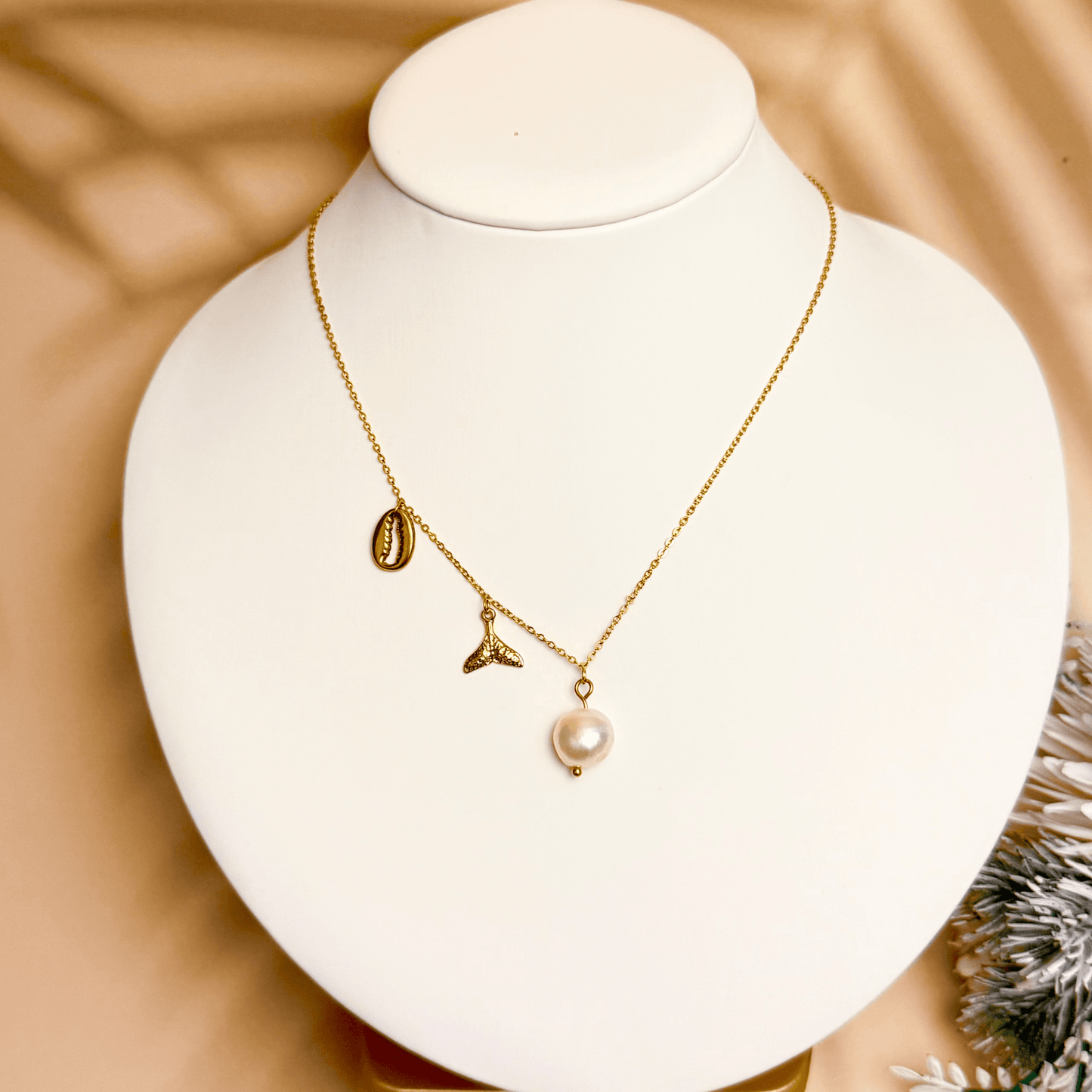 Gold necklace with pearl, whale tail, and shell charms on dainty waterproof chain