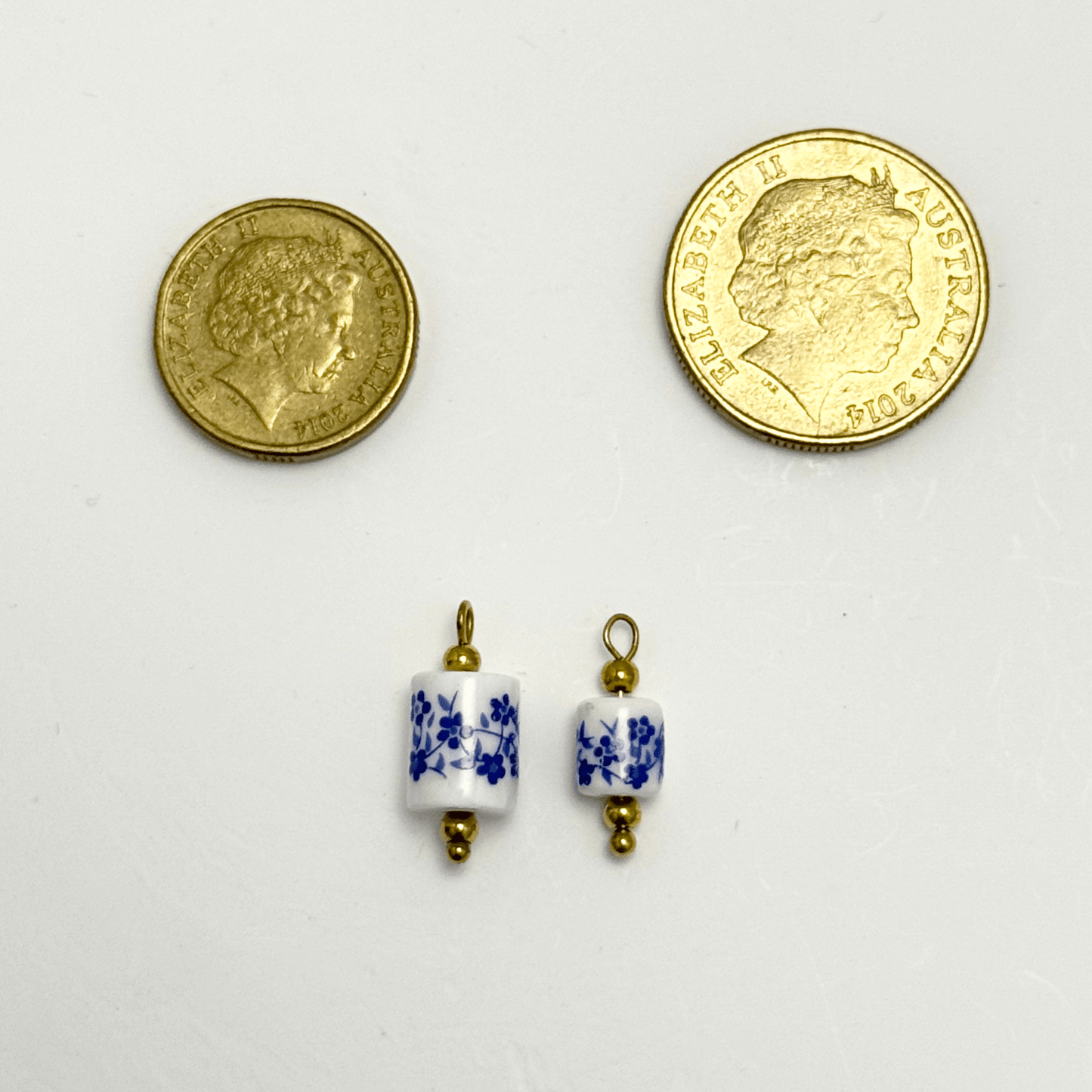 Cylindrical white ceramic charm with blue floral design and gold detailing