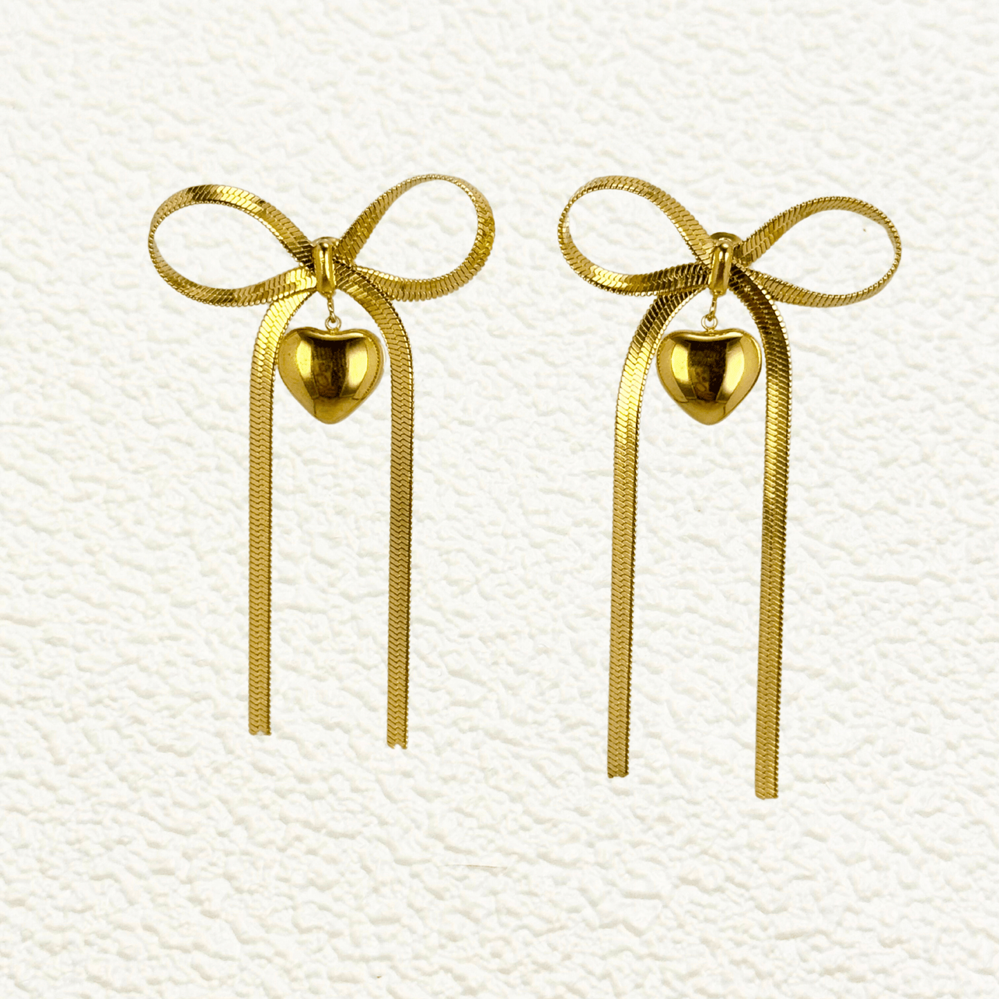 Ribbon bow drop earrings in gold and silver PVD plated stainless steel with long tails and polished heart charms